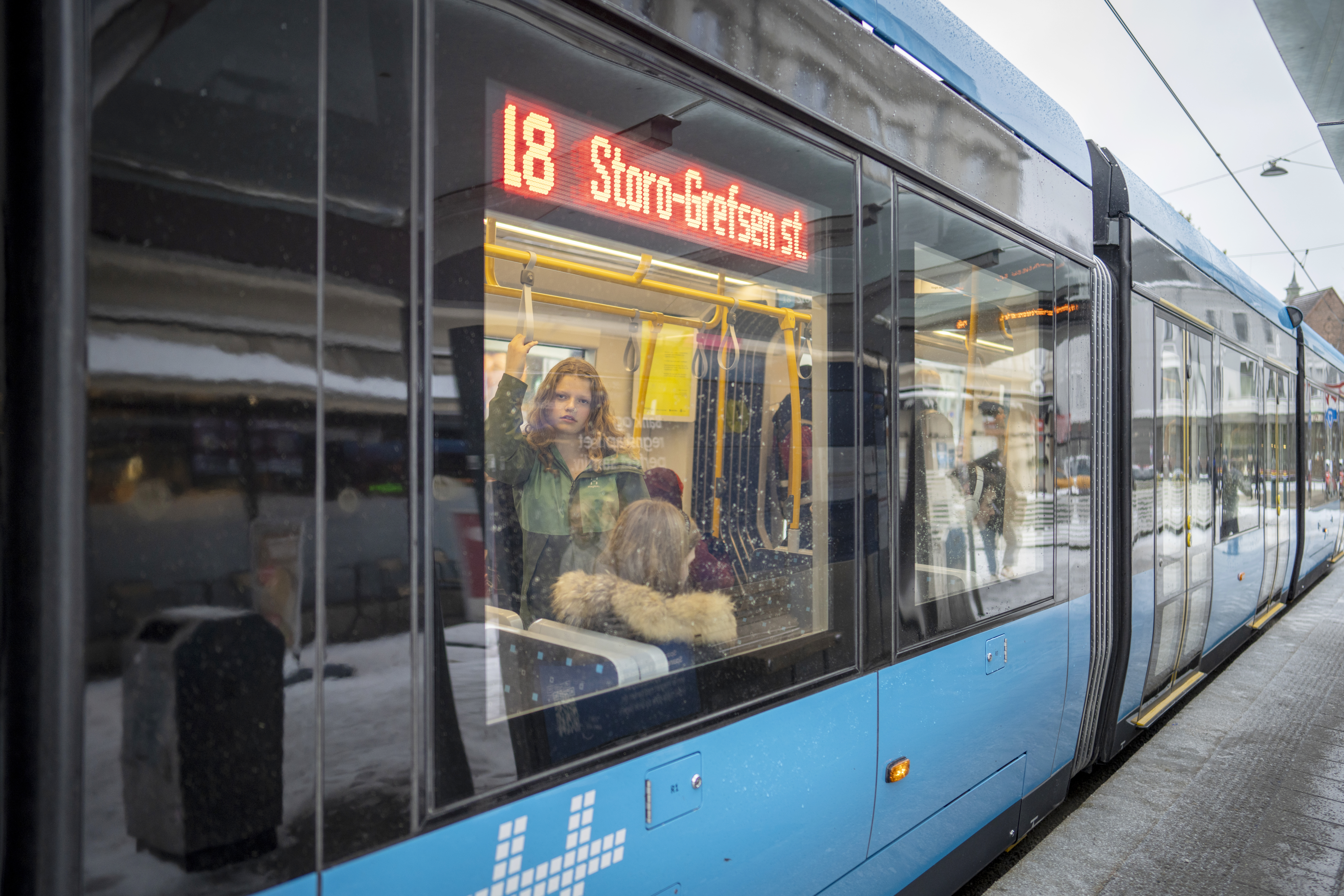 En ung kvinne ser ut igjennom vinduet på trikk nr. 18 i Oslo.