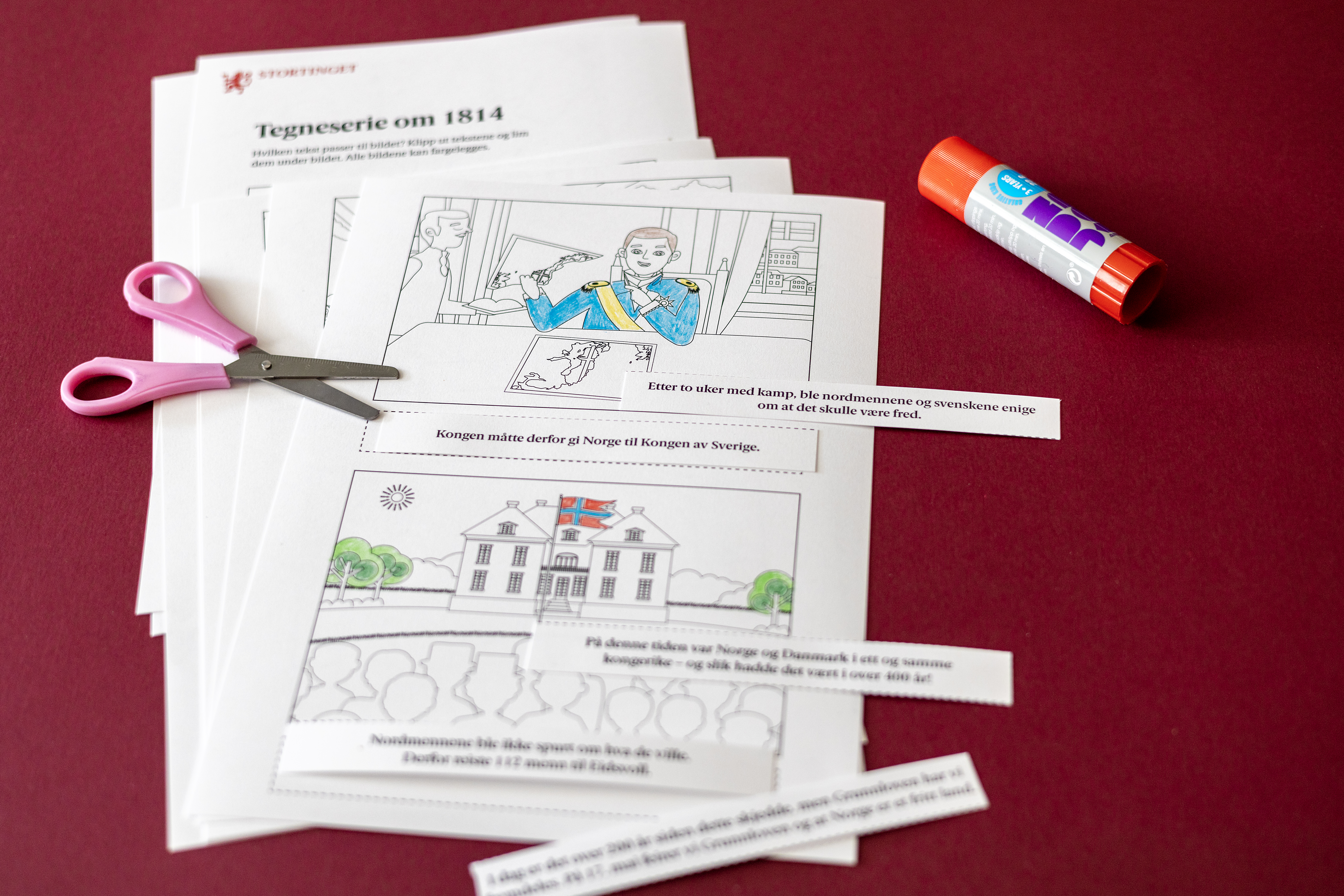 Oppgave ark ligger i en bunke. Ved siden av er det en limstift og en saks. 