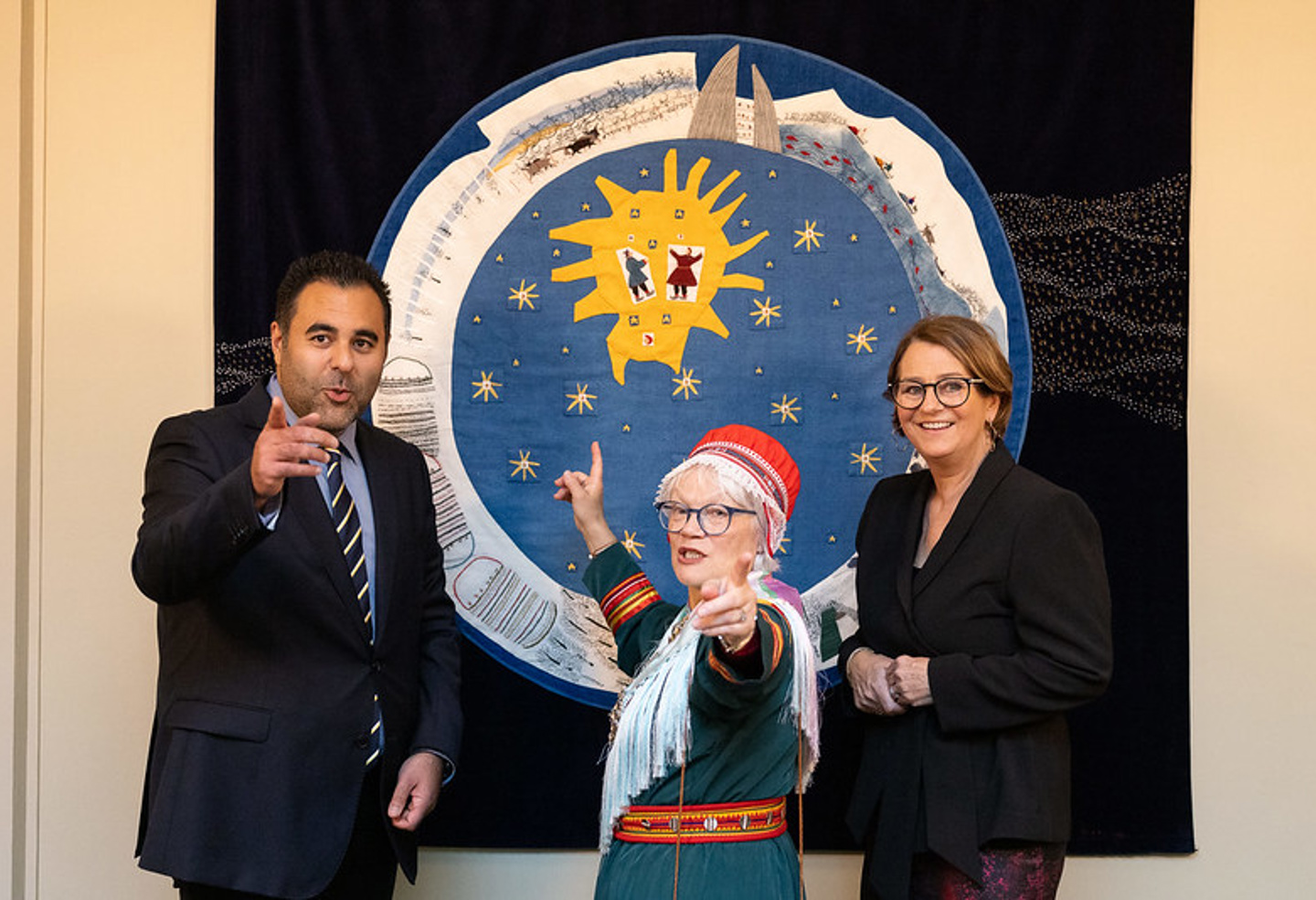 Tre personer står foran et kunstverk.