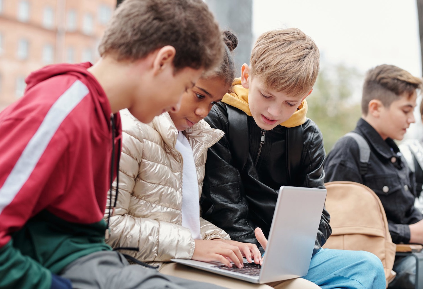 Tre barn sitter ved siden av hverandre og skriver på en pc.