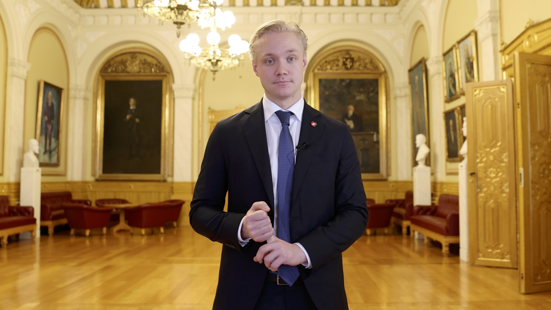 Ung mann ser inn i kamera, i Eidsvollsgalleriet på Stortinget.