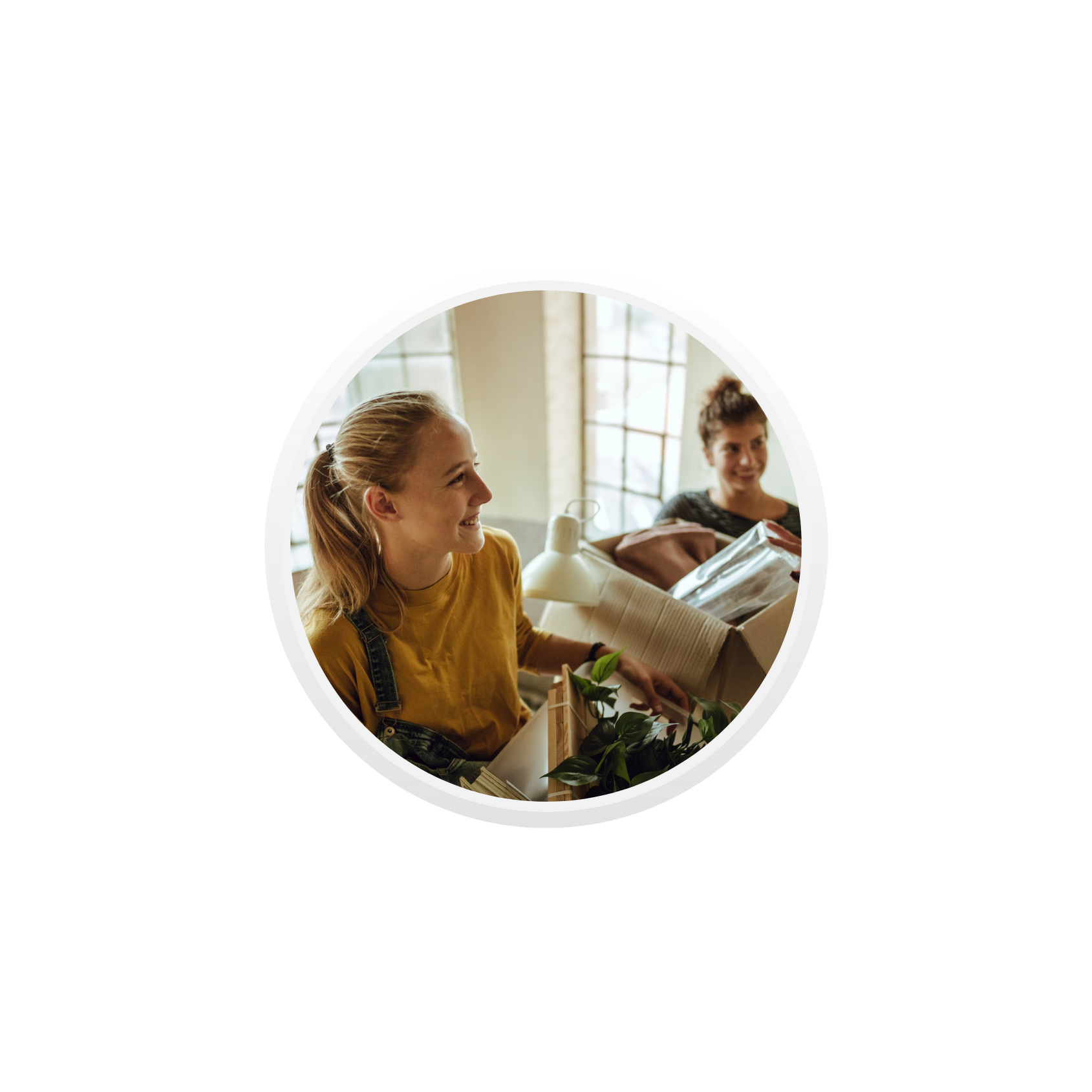 To unge kvinner bærer flyttebokser opp en trapp i en eldre bygård.