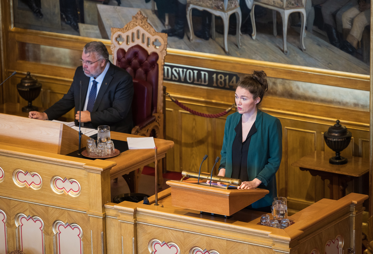 En representant står på en talerstol. Ved siden av henne sitter stortingspresidenten.