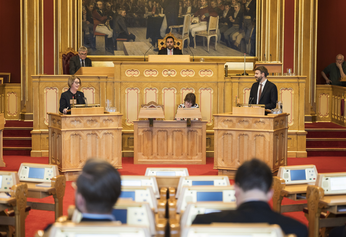 To personer står på hver sin talerstol i stortingssalen.