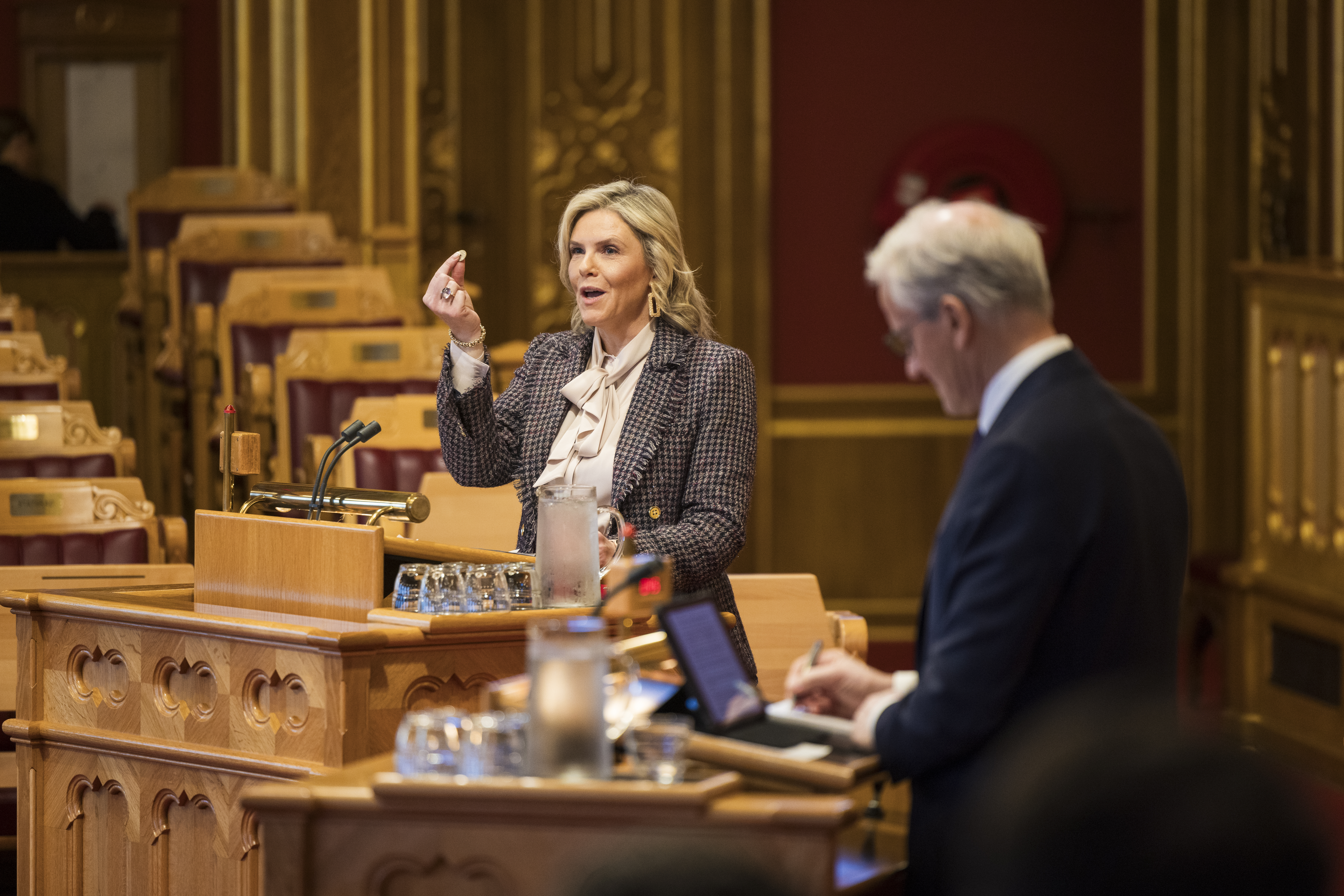 En kvinne og en mann står på hver sin talerstol i stortingssalen.