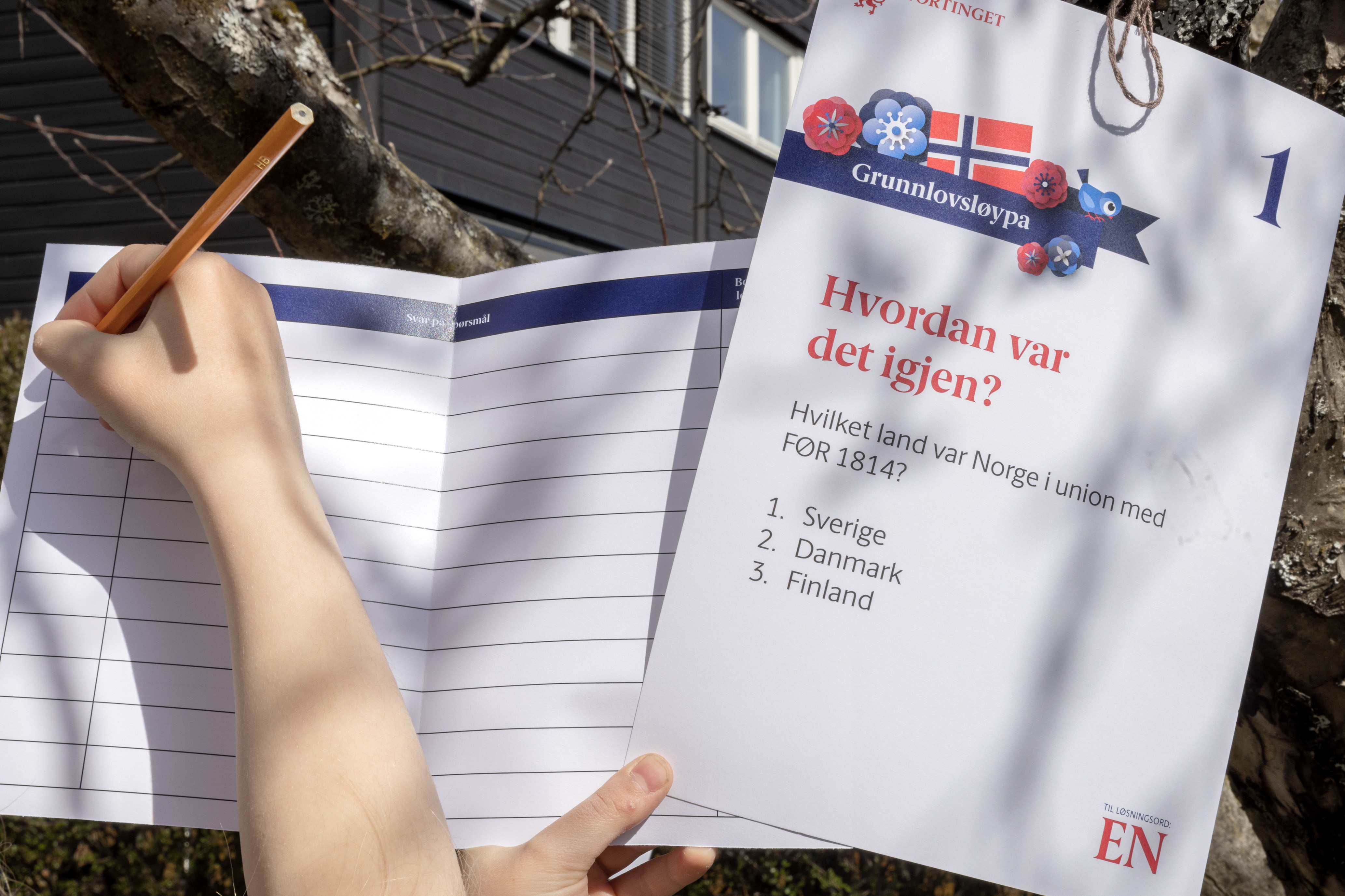 En hånd som skriver på en av postene i Grunnlovsløypa.