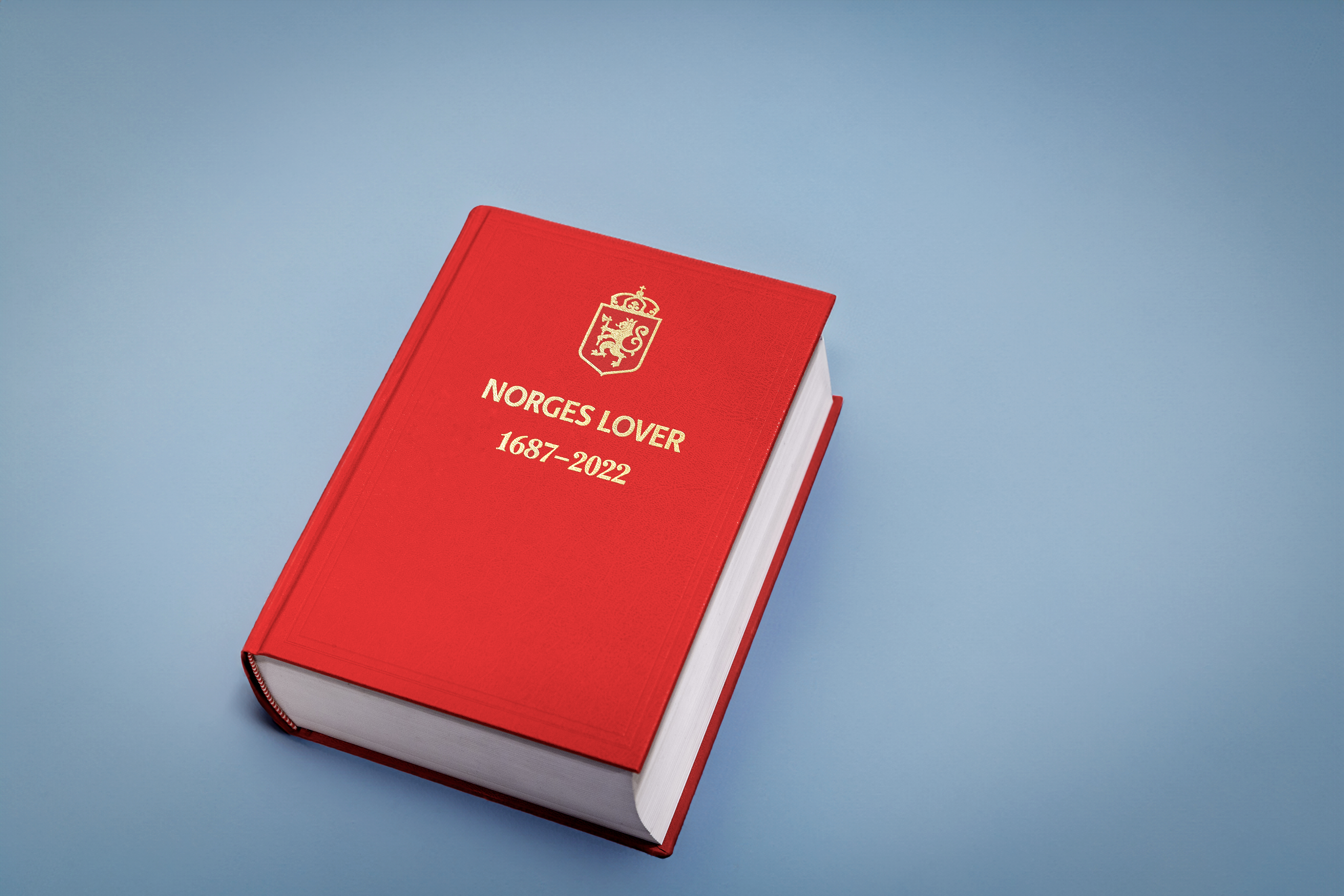 En rød bok hvor det står "norges lover" på.