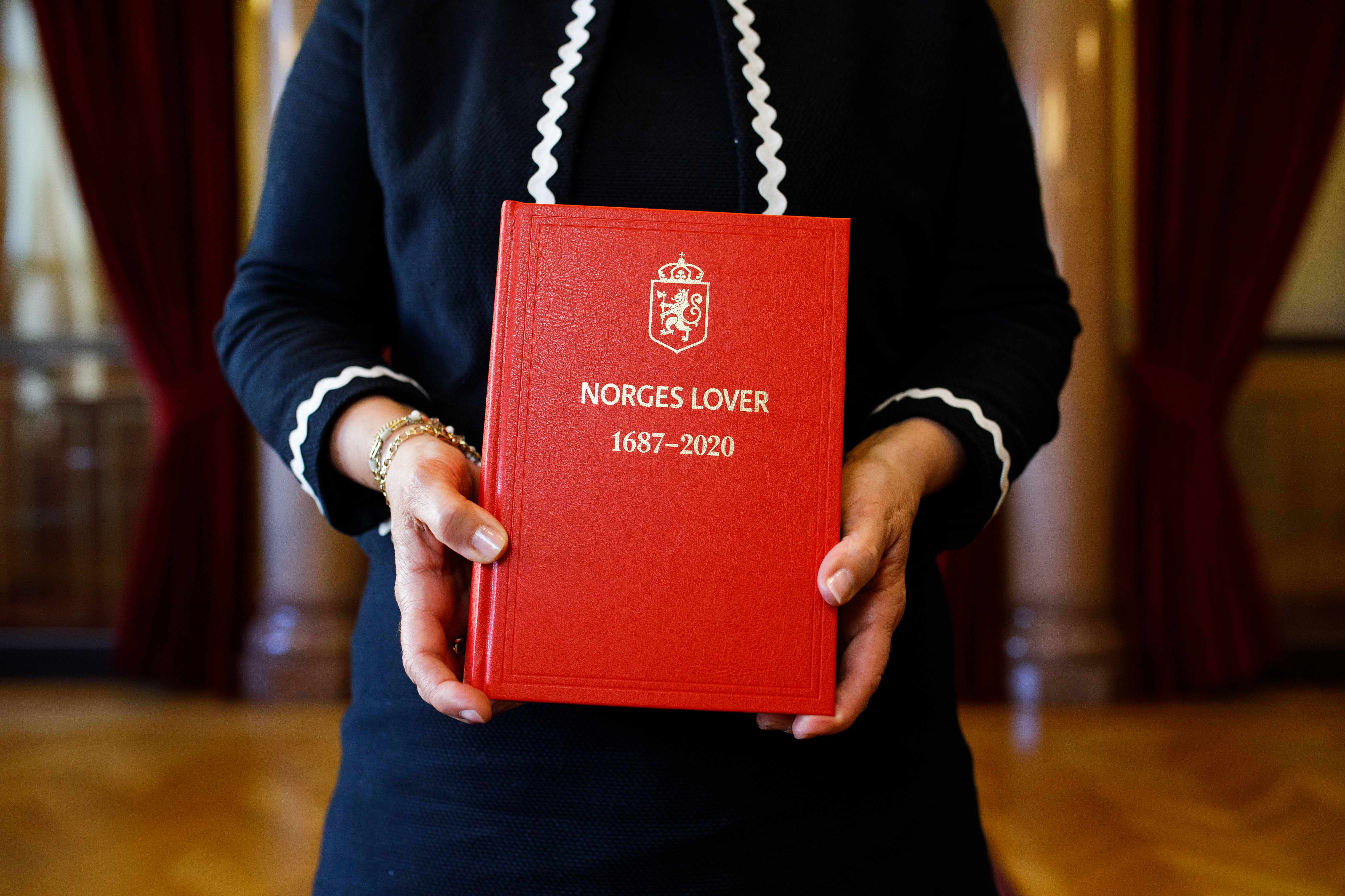 Hender som holder boken Norges lover.