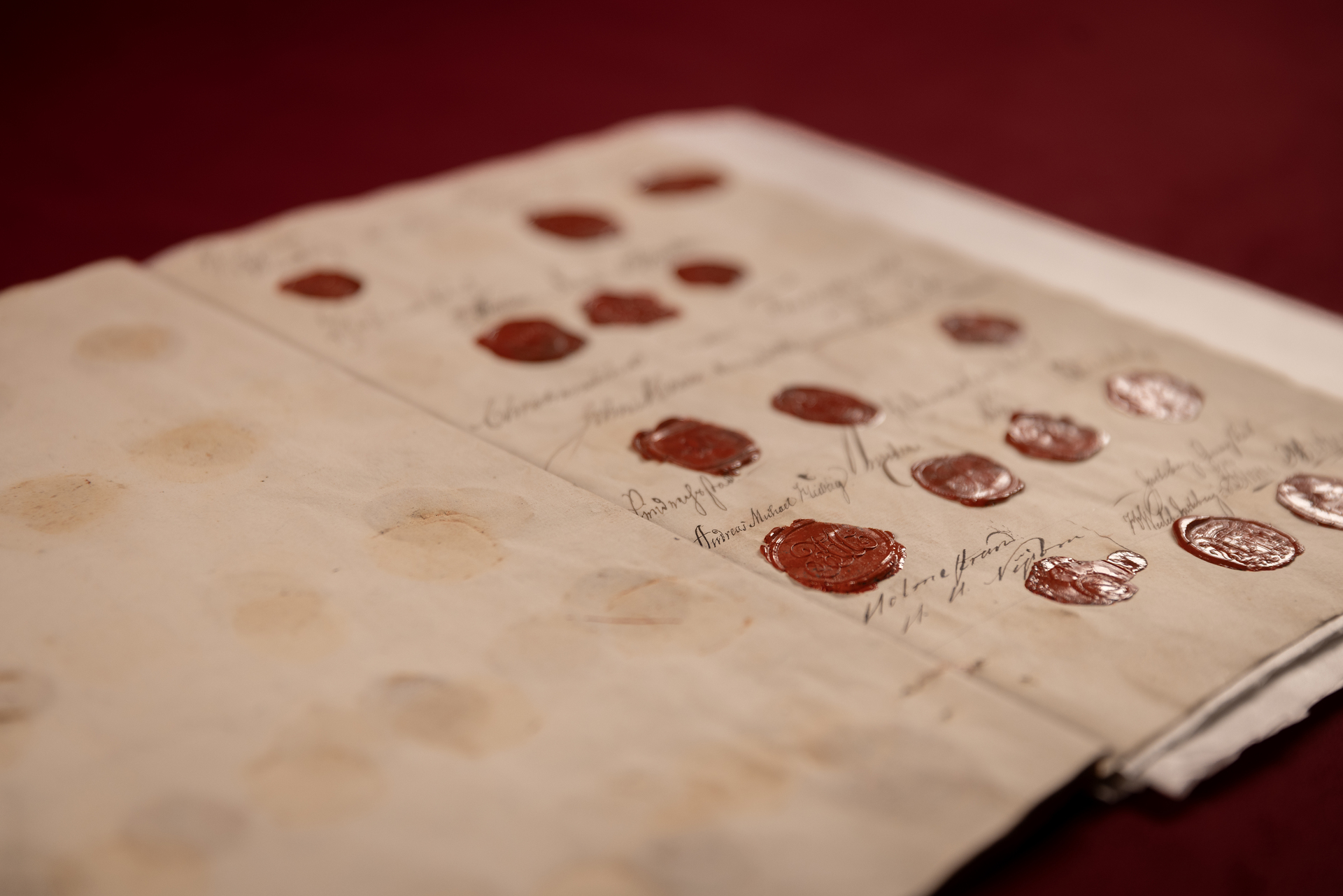 Et gammelt dokument med røde segl ligger på en rød duk.