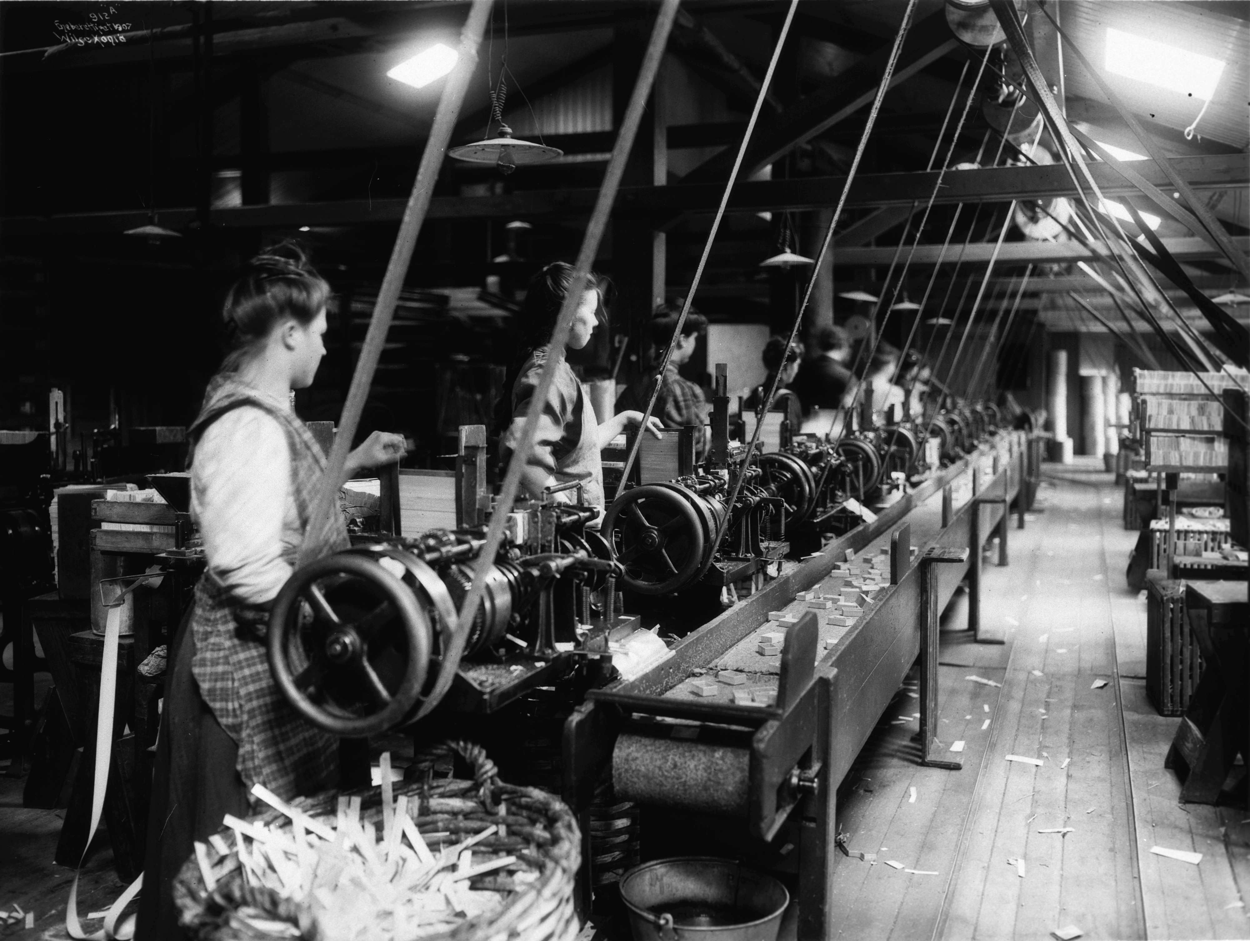 Kvinnelige arbeidere ved maskiner på fyrstikkfabrikk. 1907.