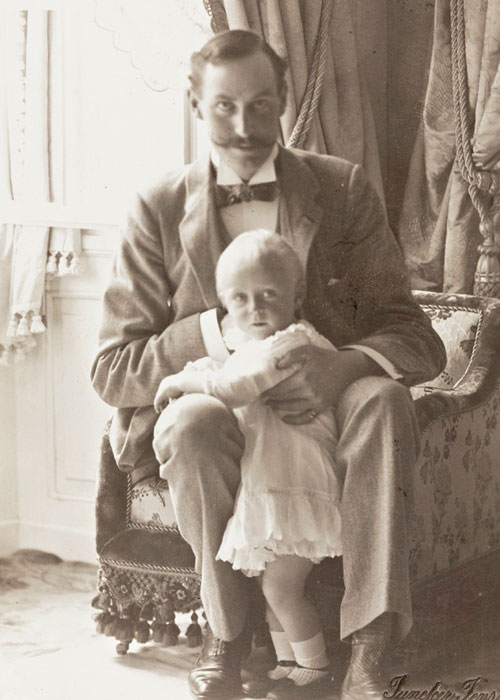 Fotografi av Kong Haakon VII med kronprins Olav i fanget