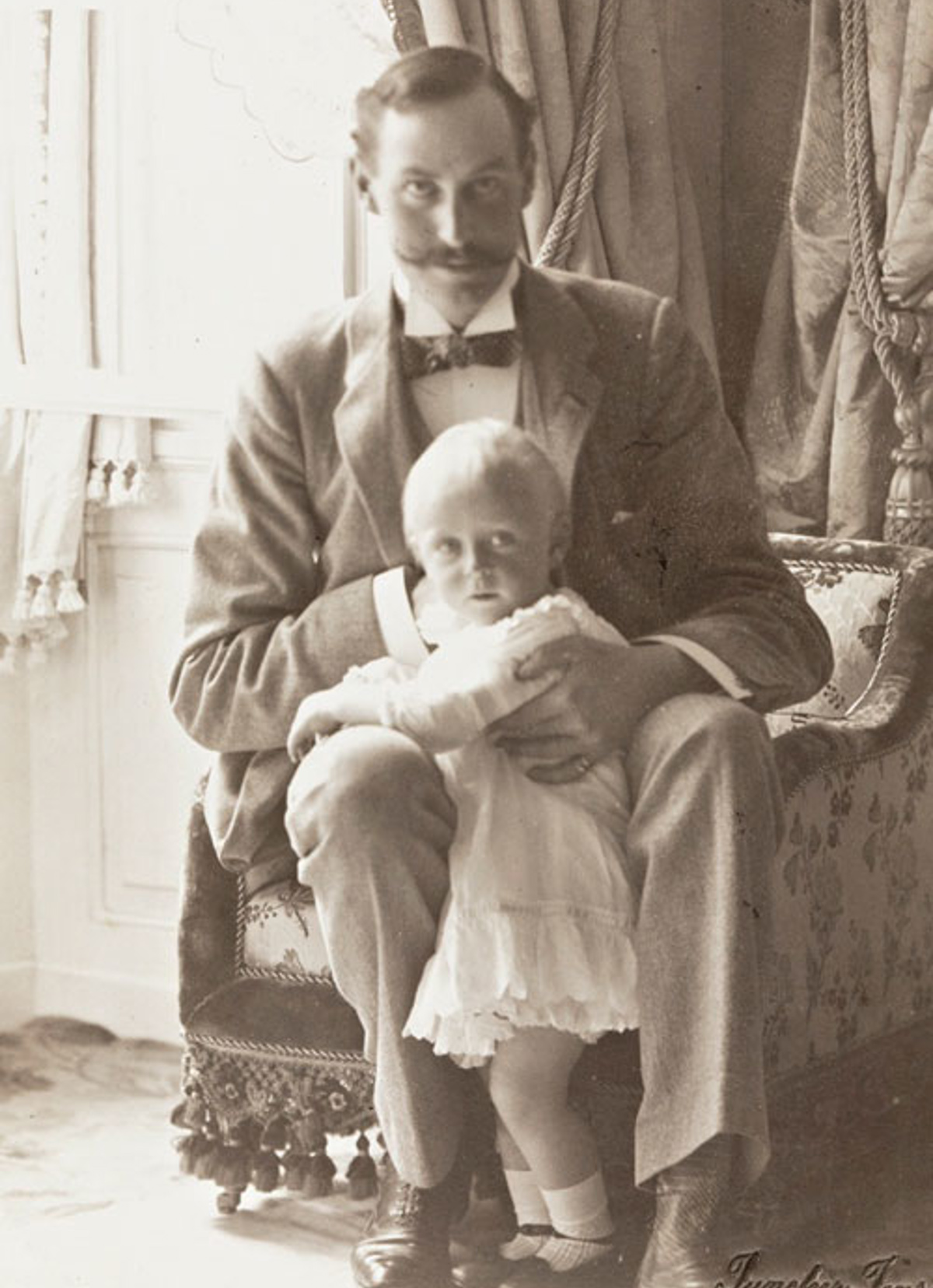 Fotografi av Kong Haakon VII med kronprins Olav i fanget