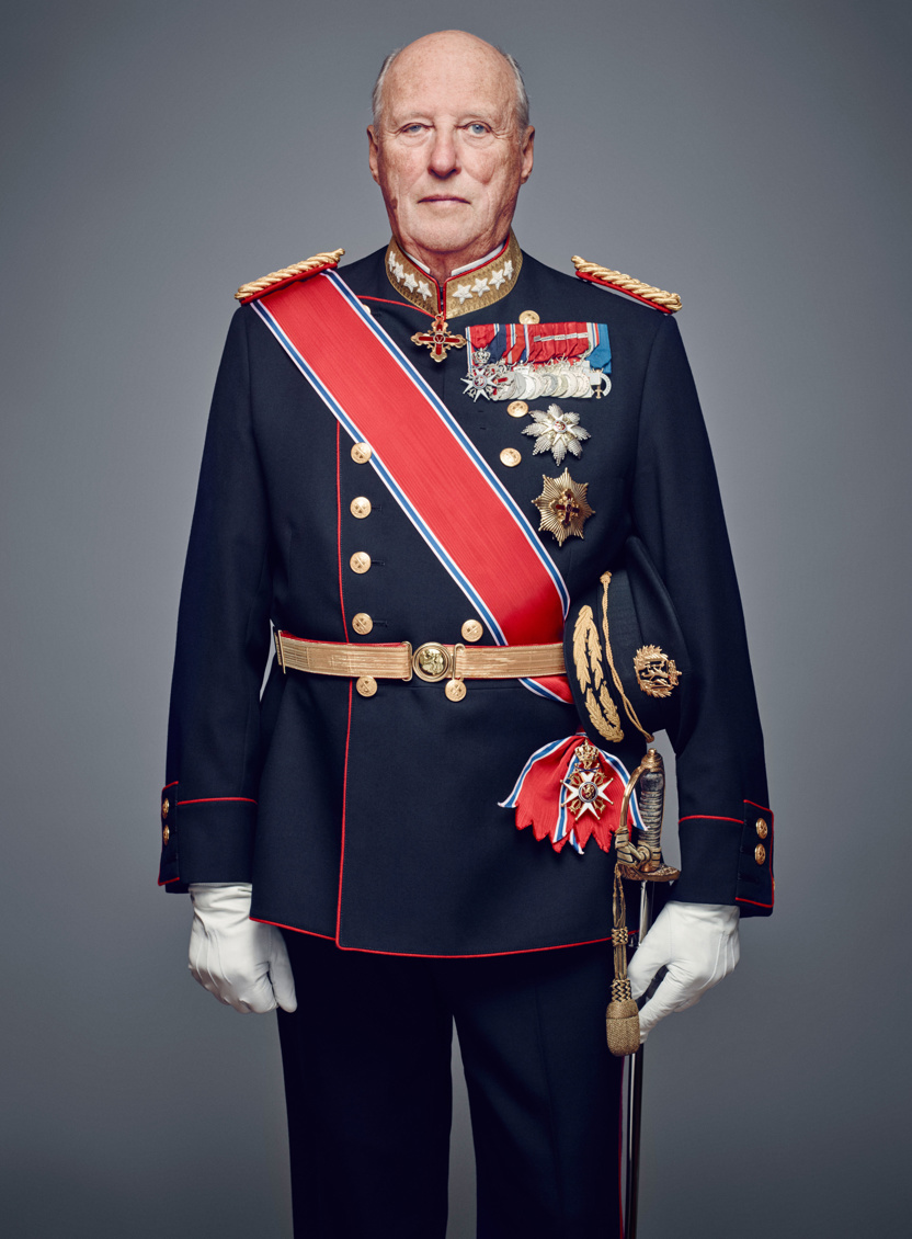 Portrettbilde av Kong Harald V. Han har på en blå uniform smykket med medaljer. 