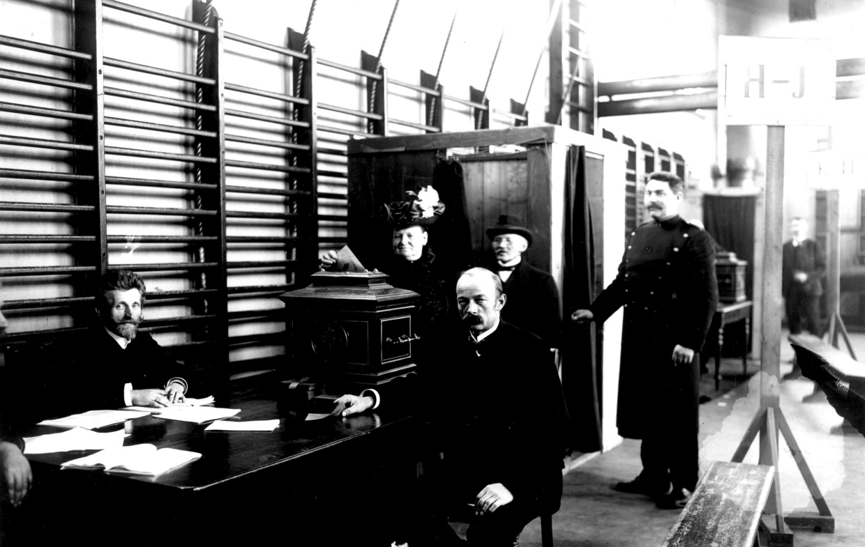 bilde i svart hviit av en mann som avlegger sin stemme i et stemmelokale i 1909.