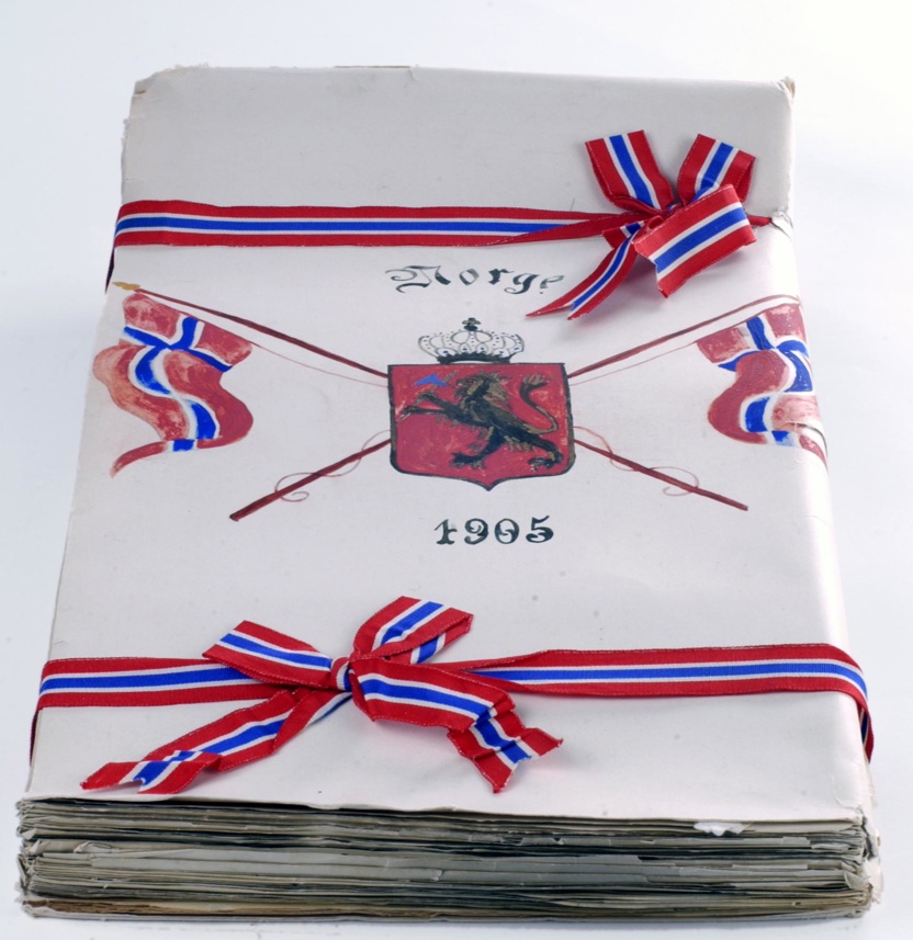 En mappe med ark inni, dekket med bånd i fargene rødt, hvitt og blått. Foran er det tegnet inn riksvåpenet, og det står "1905"
