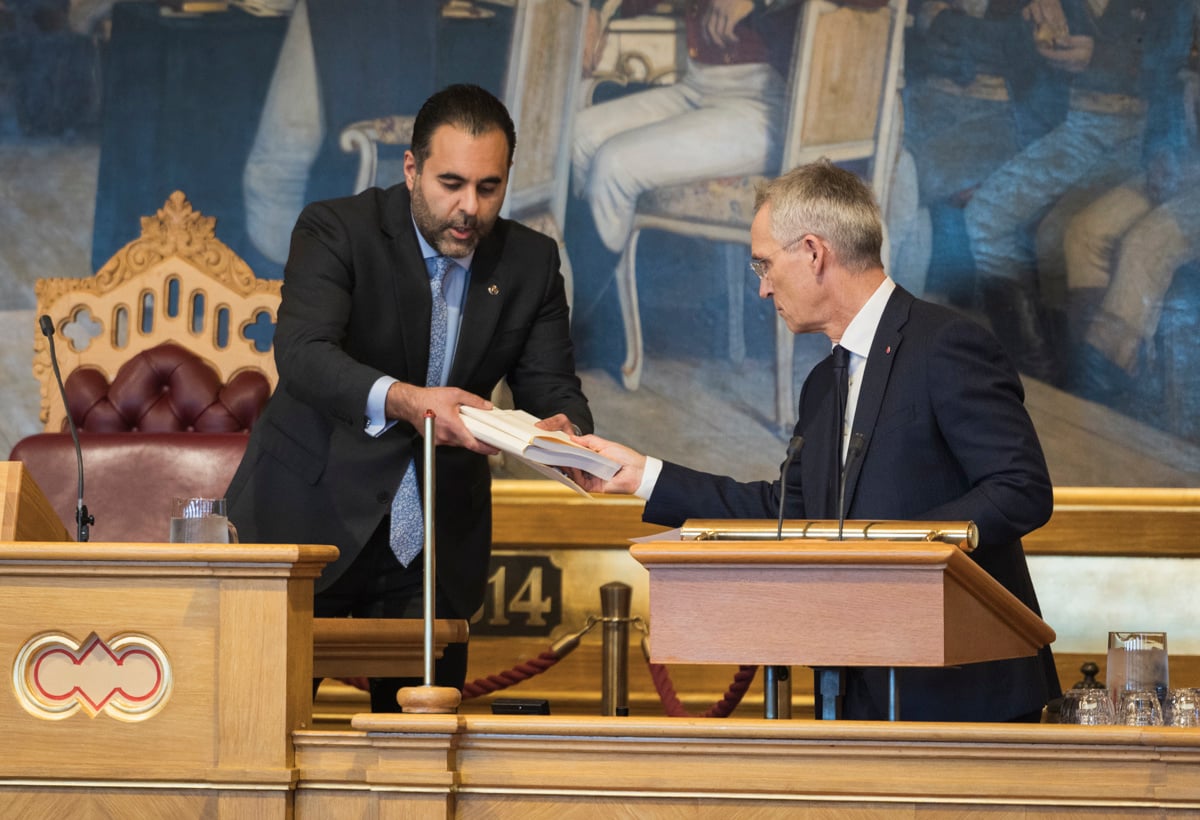 Jens Stoltenberg gir to bøker til stortingspresidenten i stortingssalen.