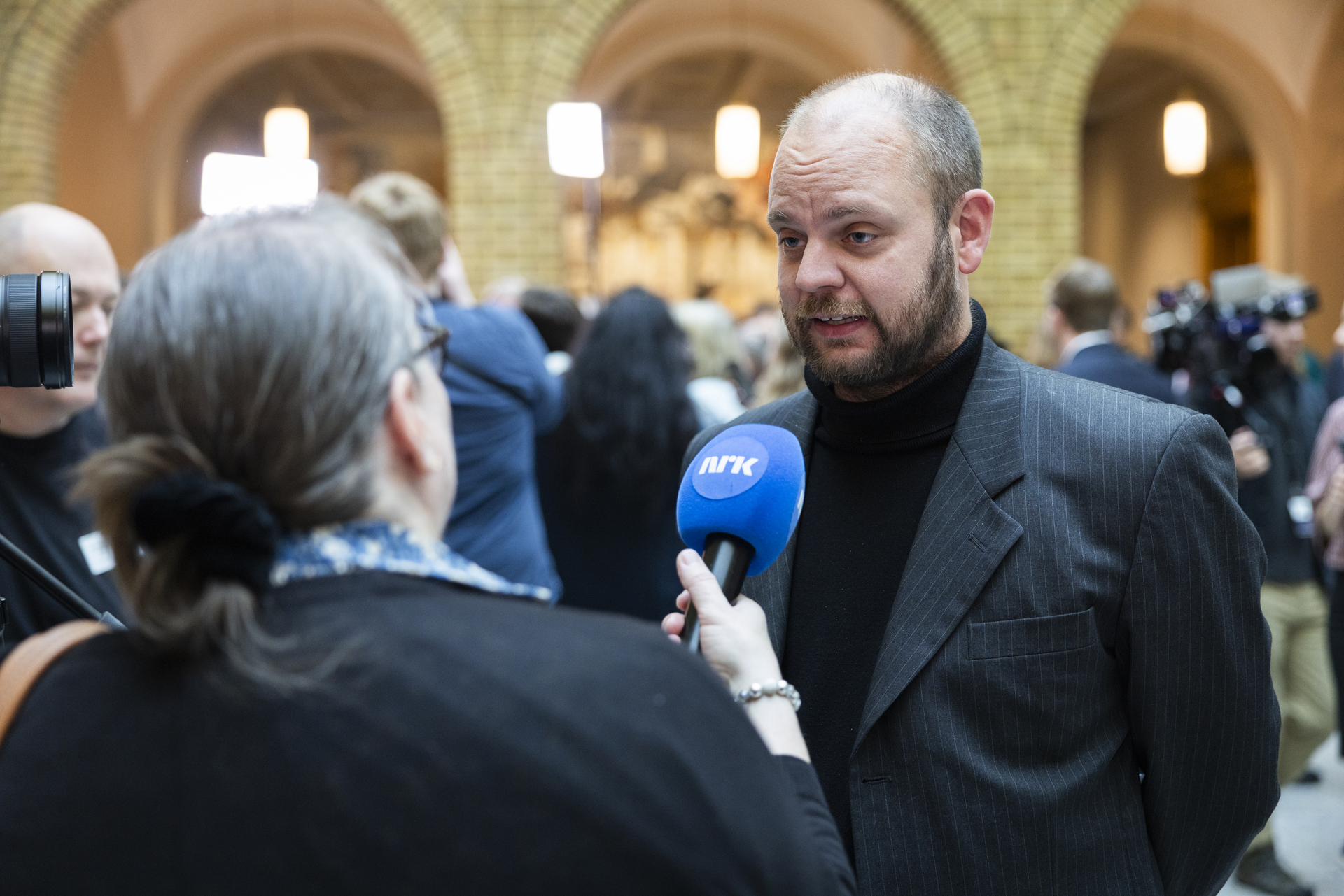 En mann blir intervjuet av NRK-journalist i vandrehallen på Stortinget.
