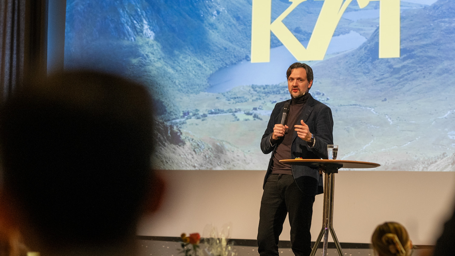 En mann snakker fra en scene. Det står KrF i bakgrunnen.