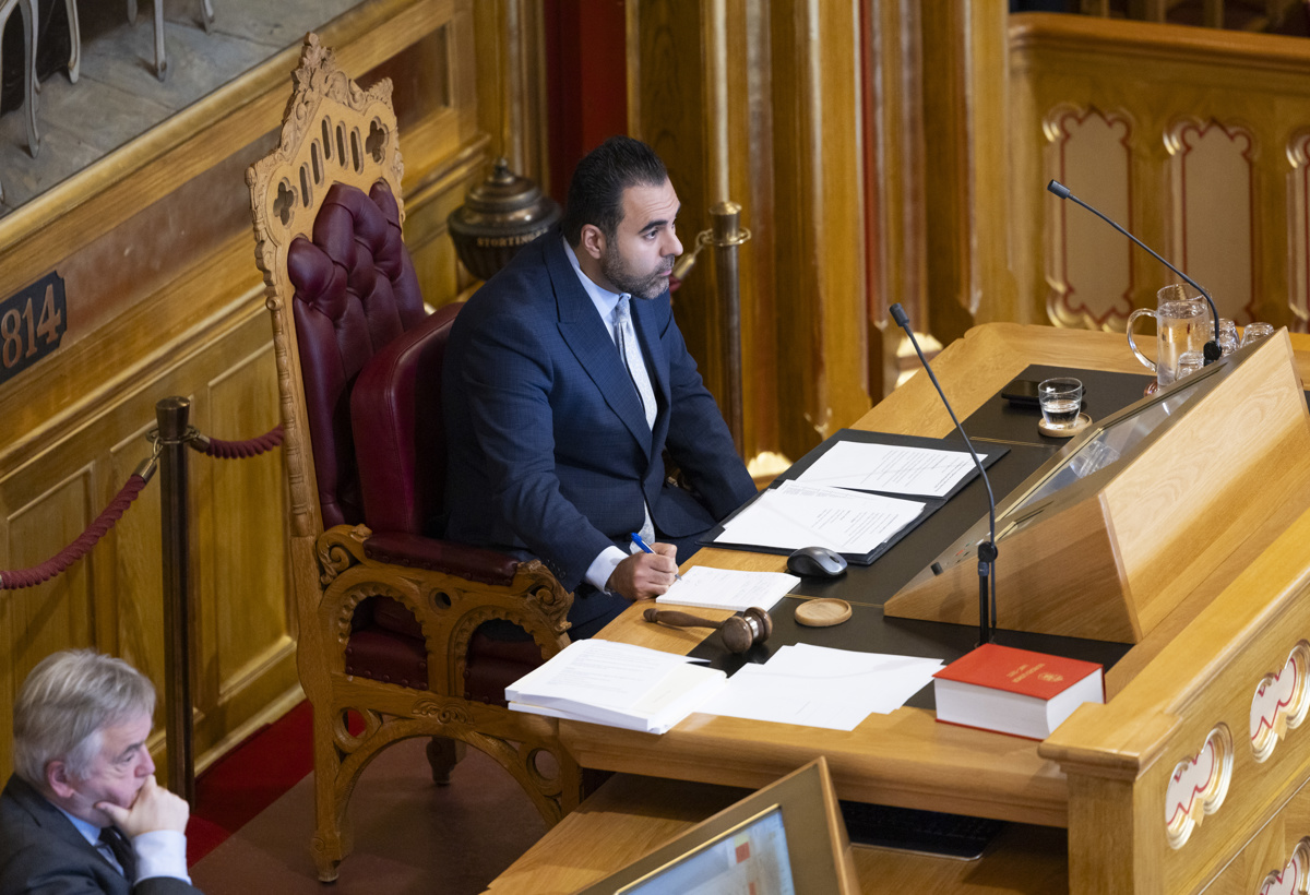 stortingspresidenten sitter på presidentpodiet og ser utover salen, mens han noterer på et ark.