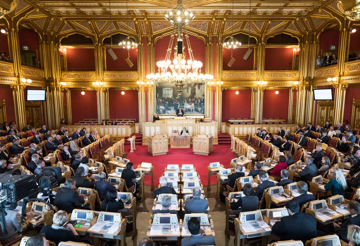 Stortingsrepresentanter sitter på plassene sine i stortingssalen.