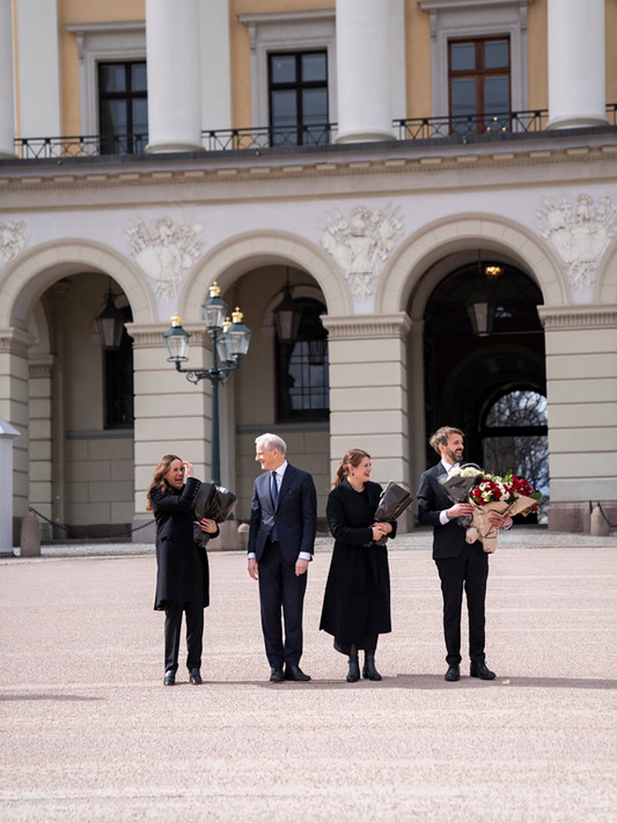 Fire statsråder med blomster foran slottet.