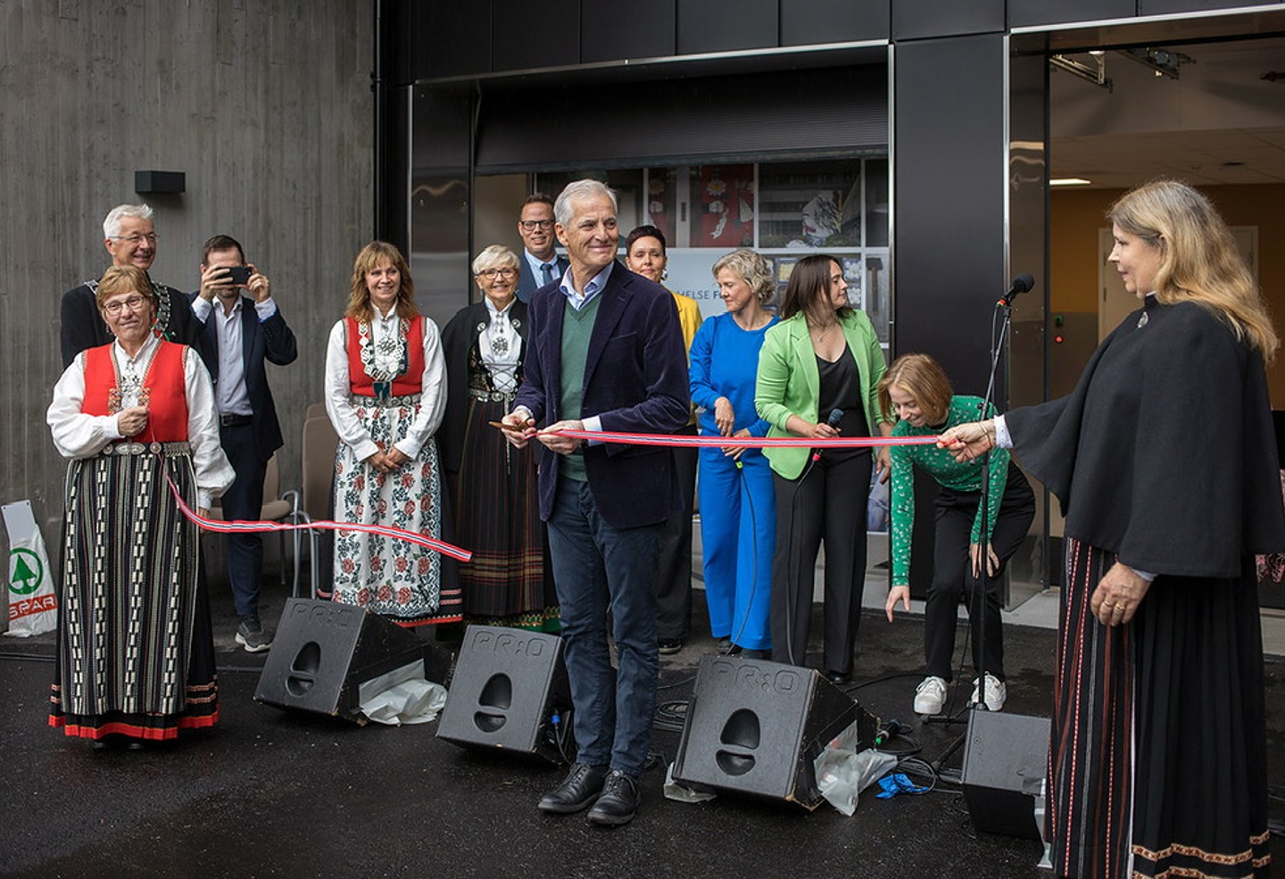 Statsministeren klipper en snor. Mennesker i bunad står rundt.