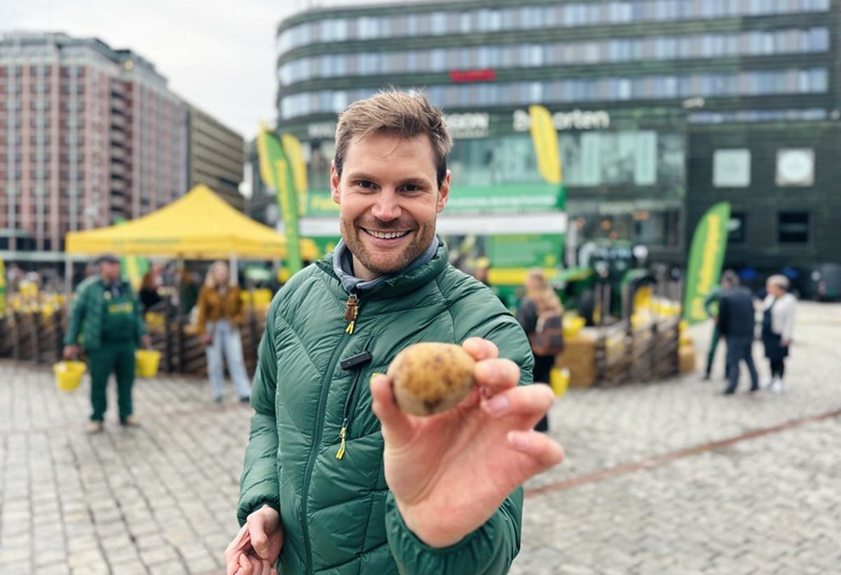 En mann smiler og holder fram en potet.