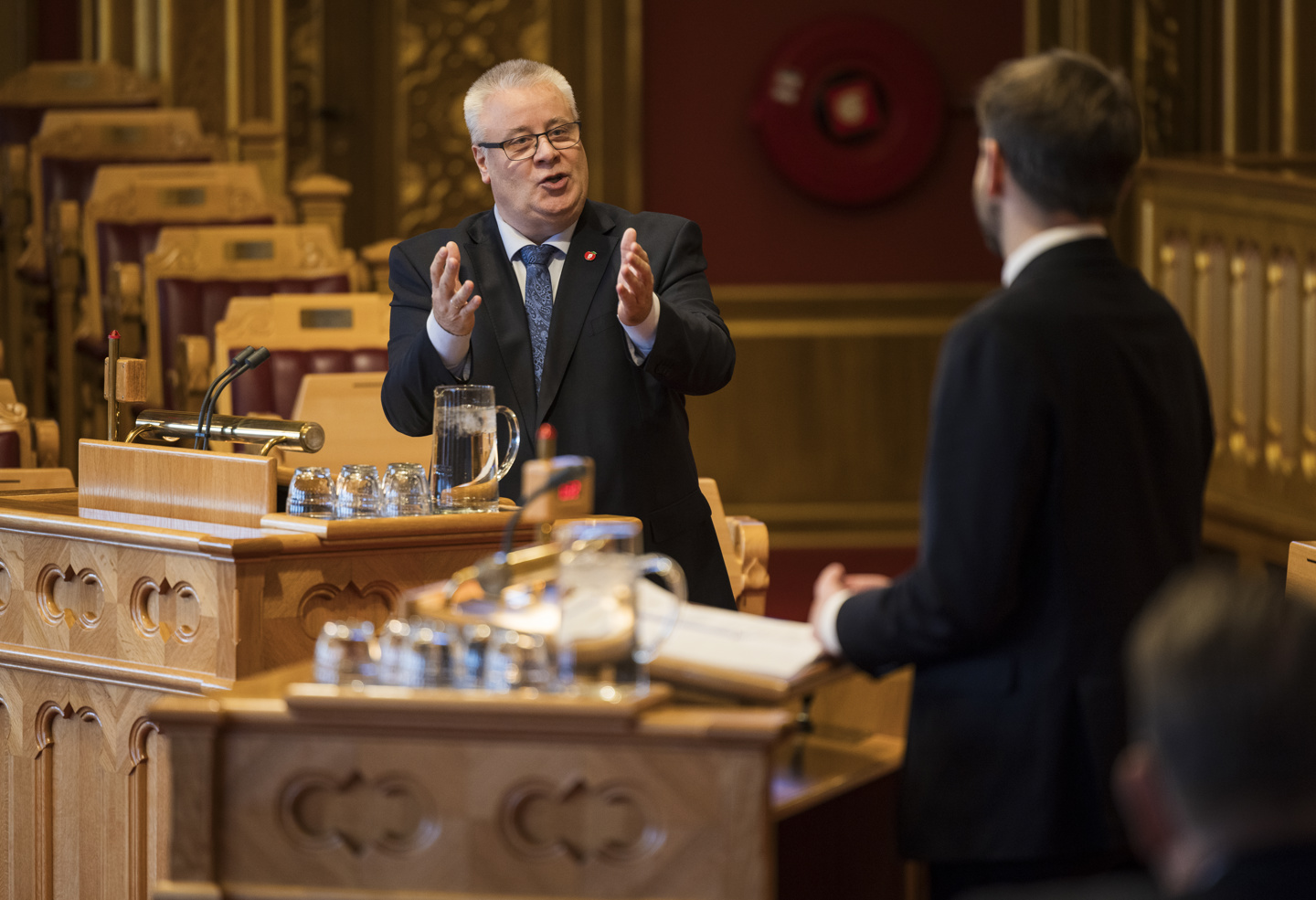 To personer står på hver sin talerstol i stortingssalen.
