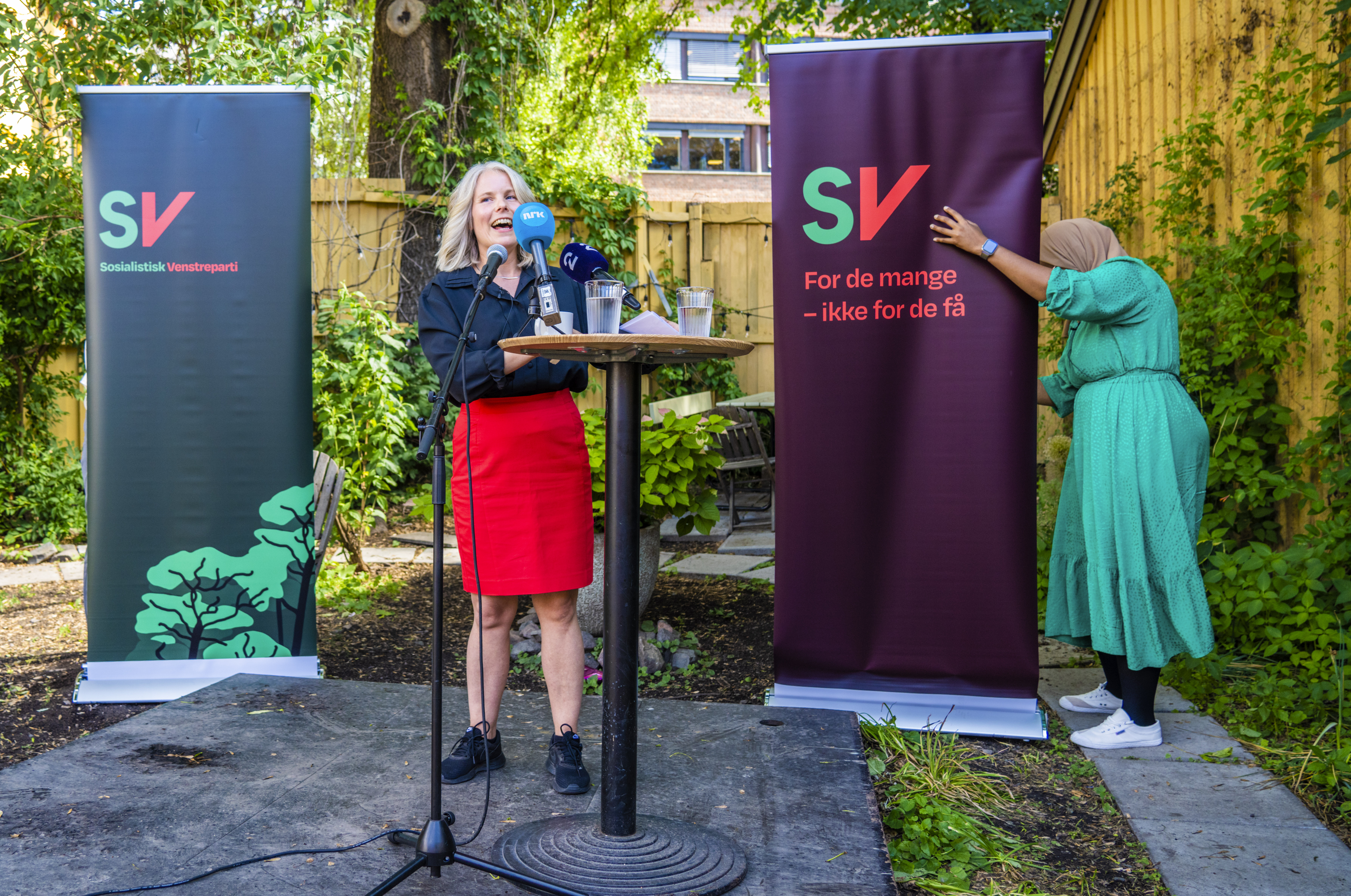 SV-leder Kirsti Bergstø. Nestleder Marian Hussein passer på flaggene med partilogoen i bakgrunnen.