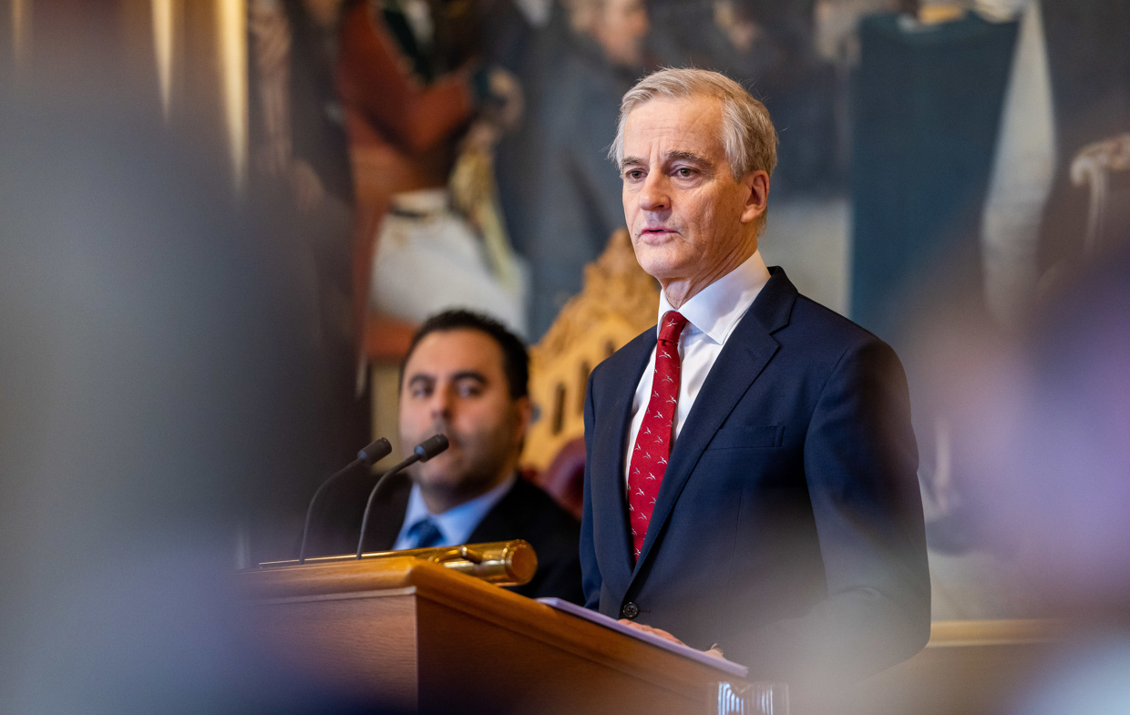 Jonas Gahr Støre holder innlegg i stortingssalen. Masud Garahkhani sitter i bakgrunnen.