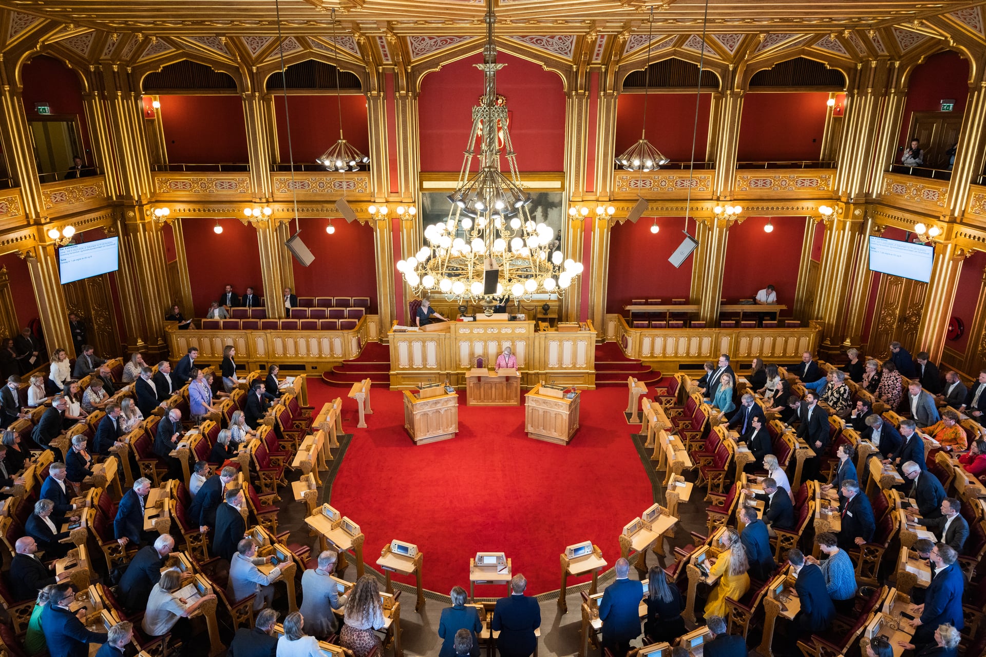 Mange stortingsrepresentanter sitter i stortingssalen. 
