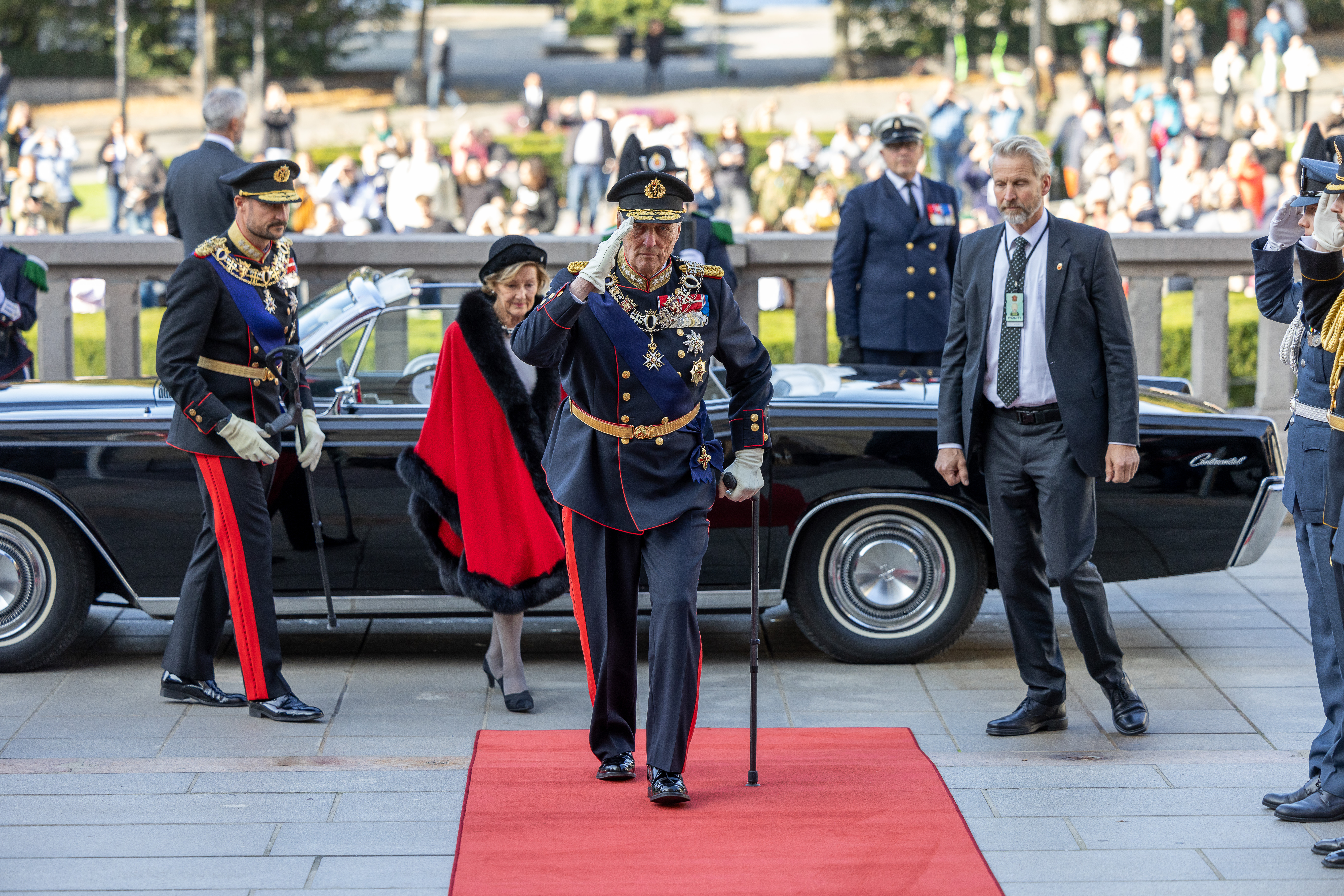 Kongen, Dronningen og Kronprinsen på vei ut av en bil foran Stortinget.