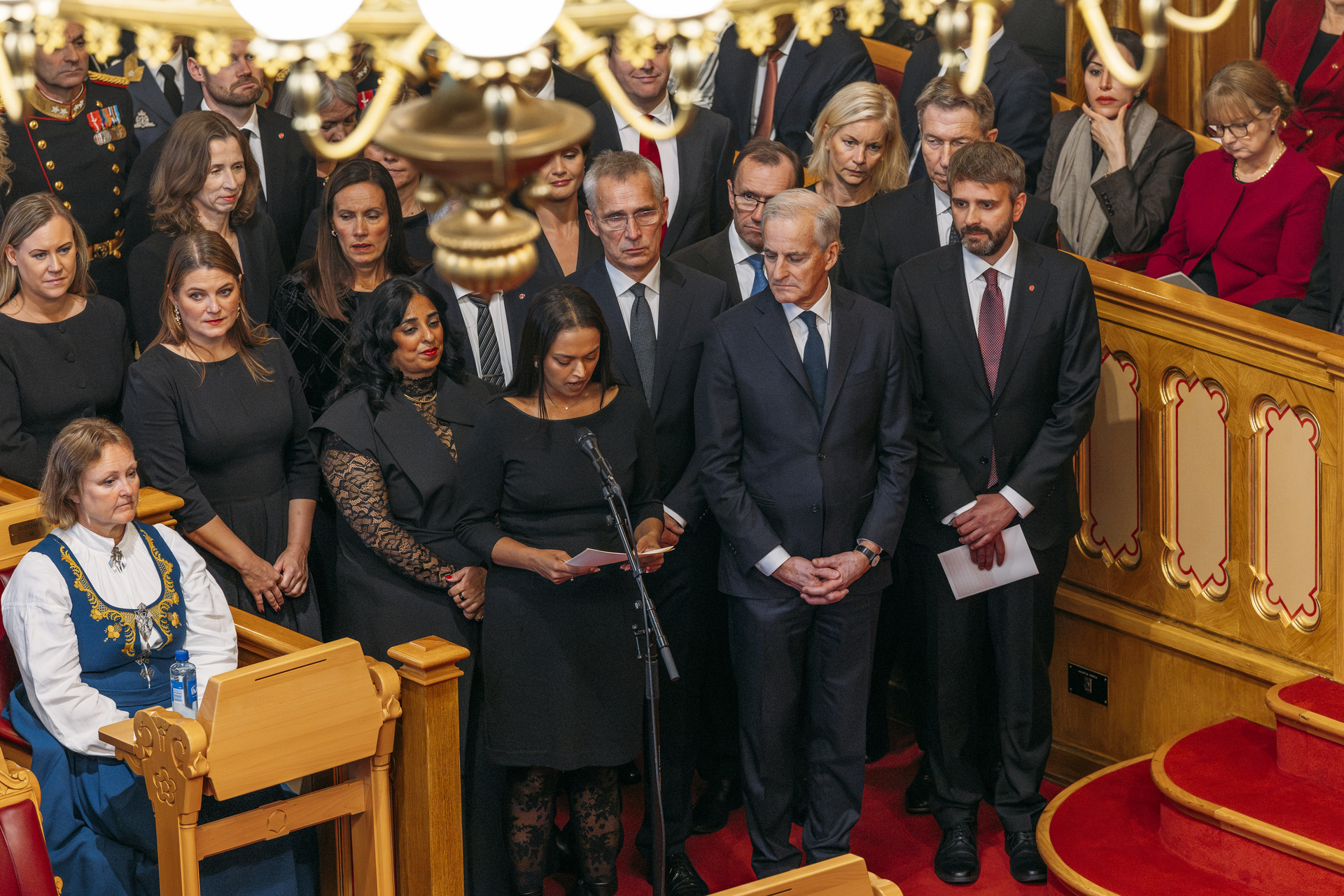 Regjeringen står samlet. Et av medlemmene leser fra et ark.
