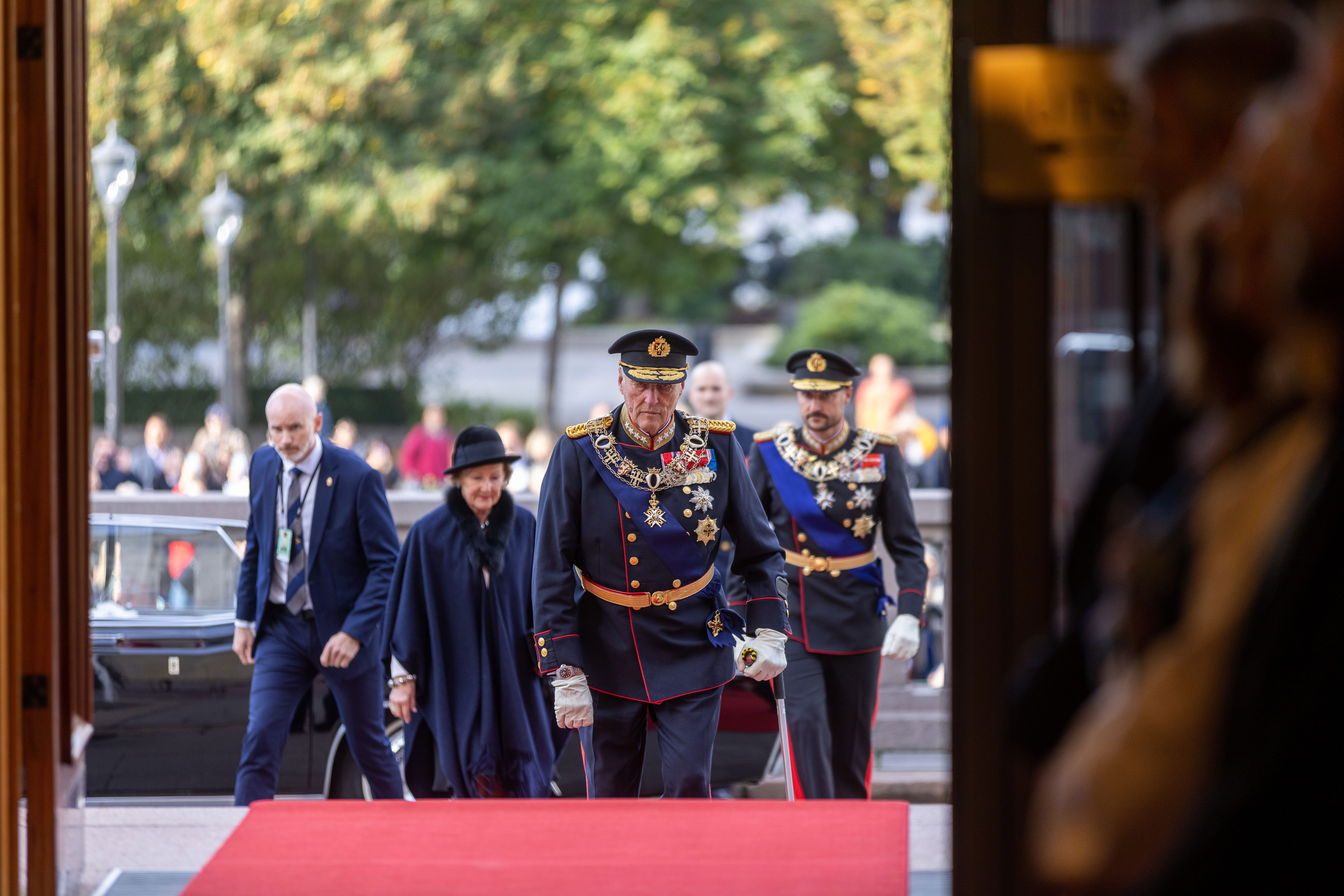 Kongen går inn hovedinngangen på Stortinget. Dronningen og kronprinser er rett bak.