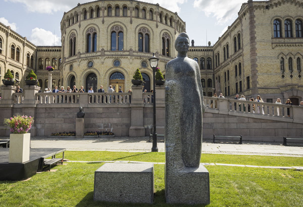En statue av en kvinne står foran stortingsbygningen.