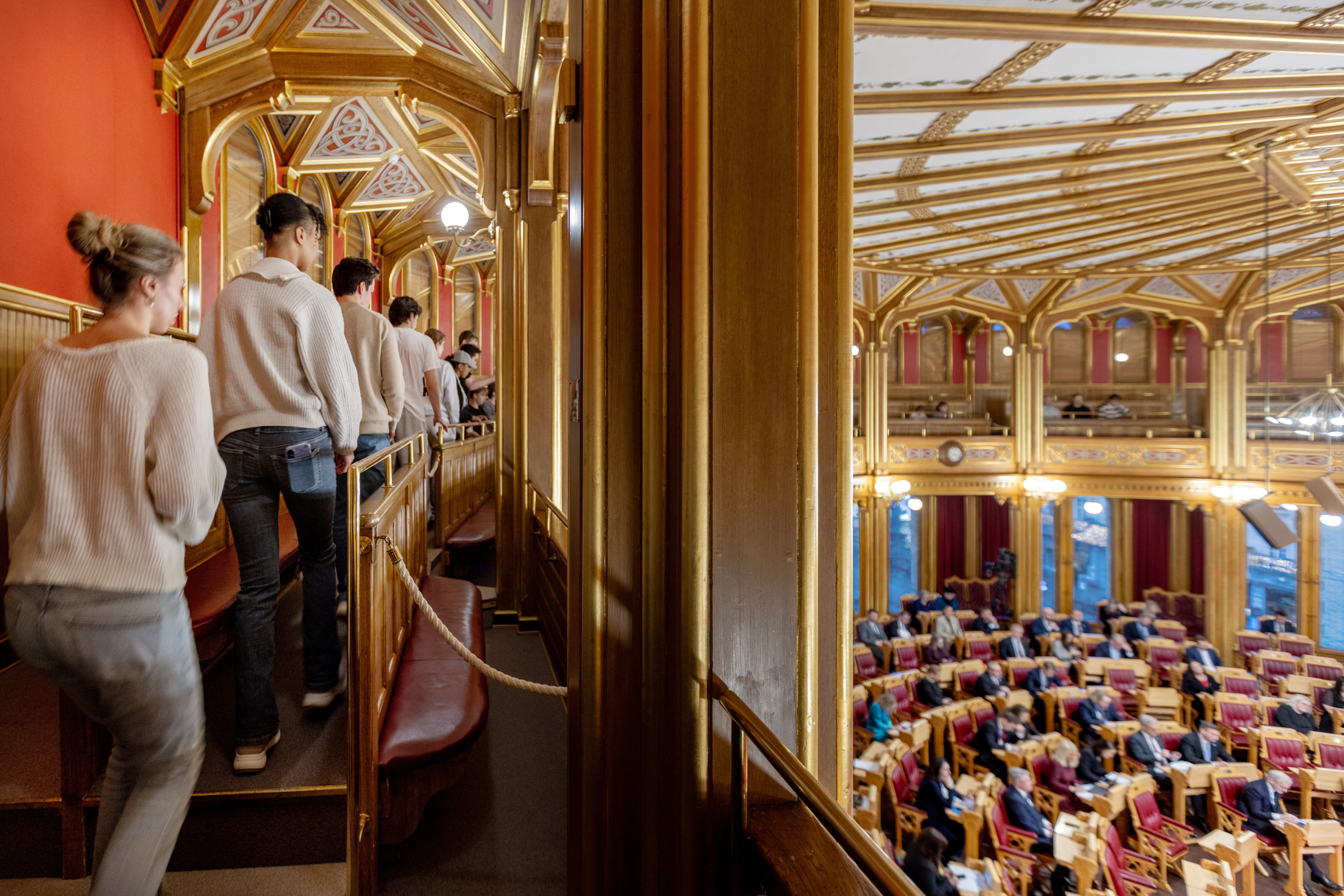 Elever går i rekke på galleriet i storitngssalen. Nedenfor kan man se stortingssalen