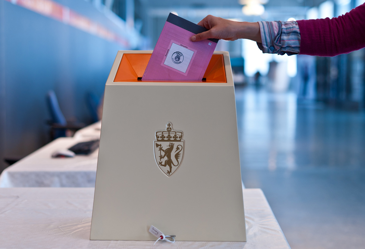 En person legger en stemmeseddel i en valgurne.