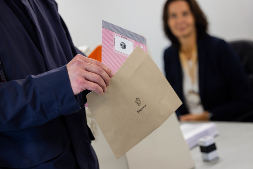 En hånd legger en stemmeseddel i en konvolutt