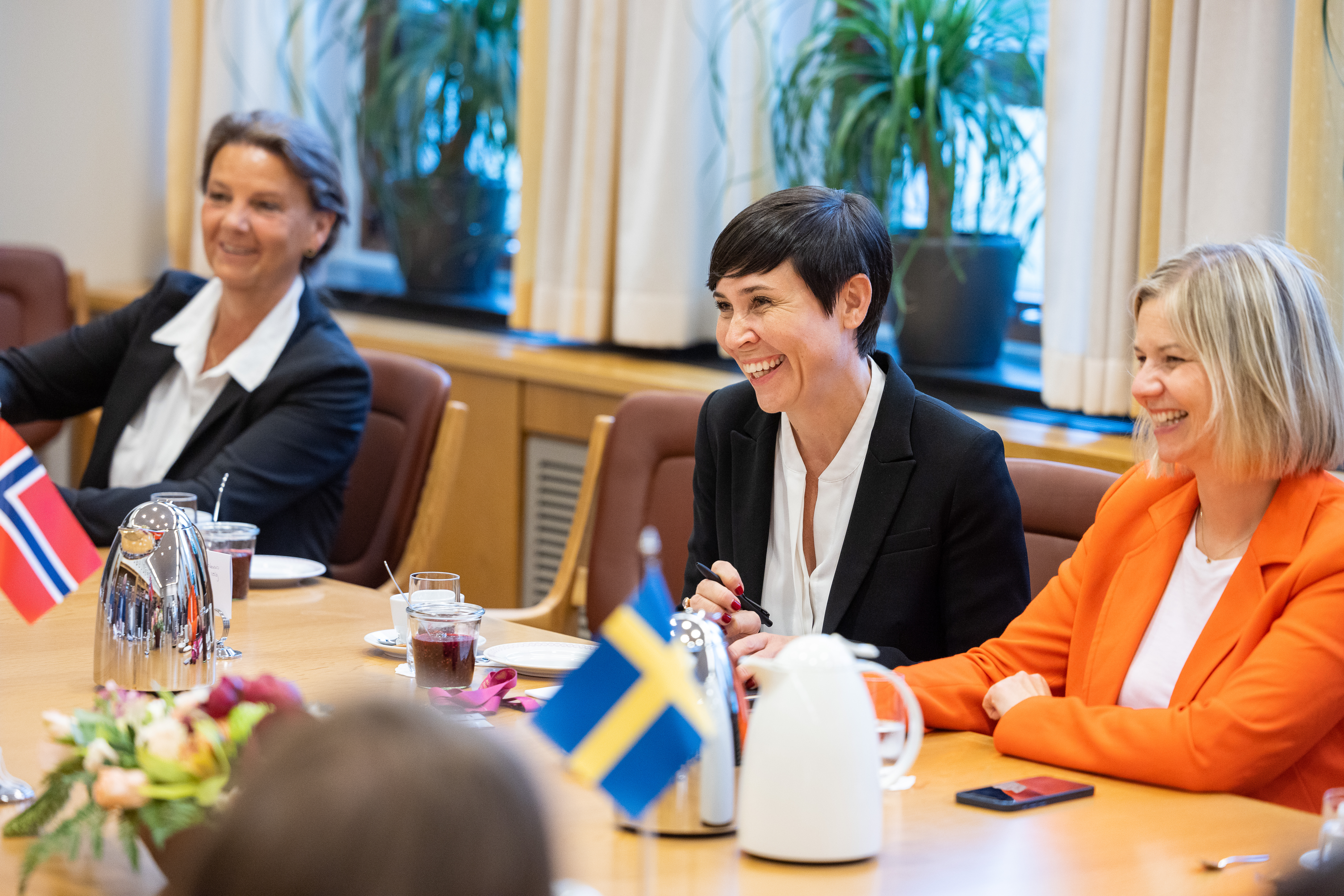 Tre personer sitter rundt et bord. 