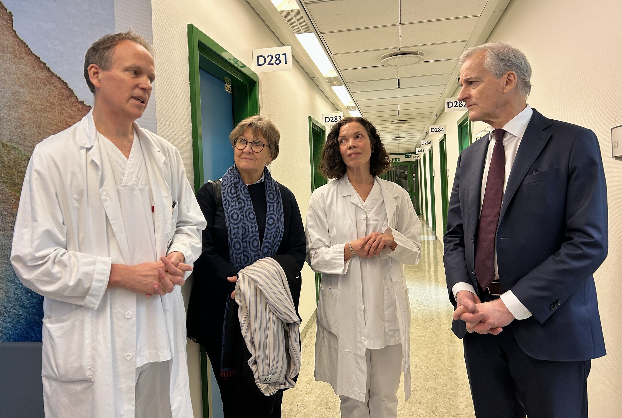 Fire mennesker står og prater. To av dem har på legefrakk.