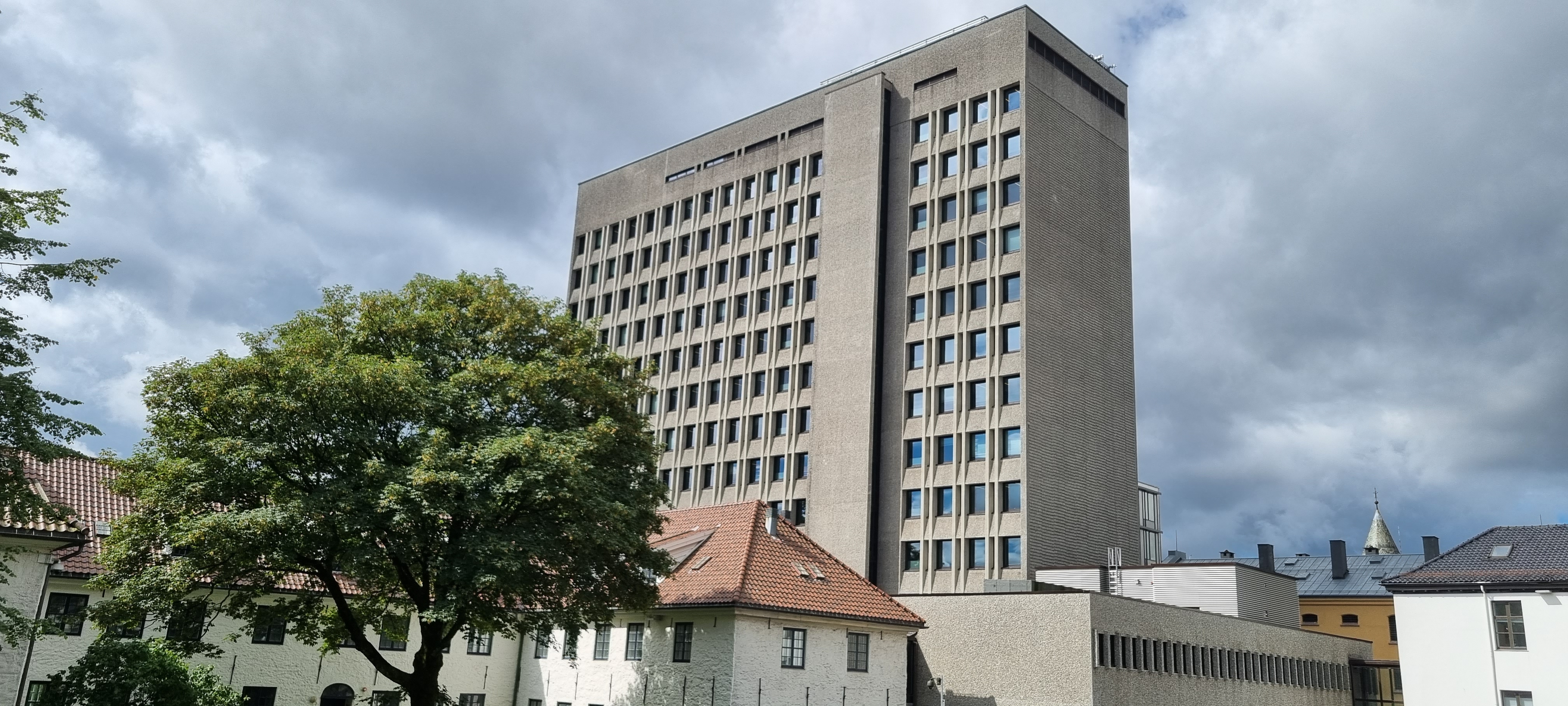 Høy betongbygning med gråblå himmel i bakgrunnen. Foto farger av Bergen rådhus.