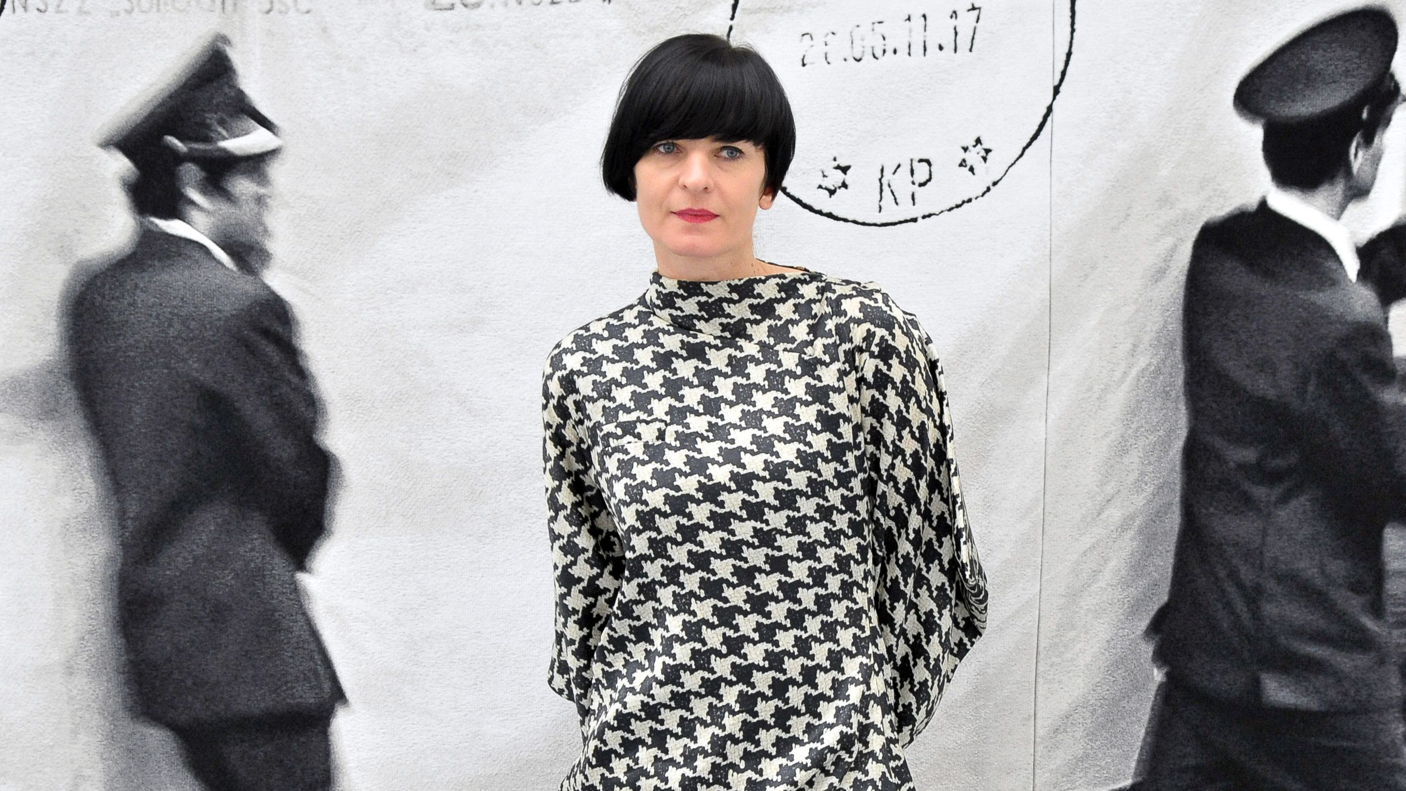 En kvinne i svart og hvit kjole poserer for kamera.