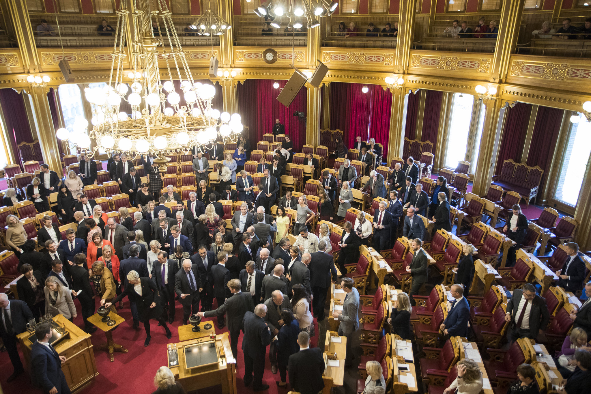 Stortingssalen. Alle representantene går mot en urne og legger lapper i.