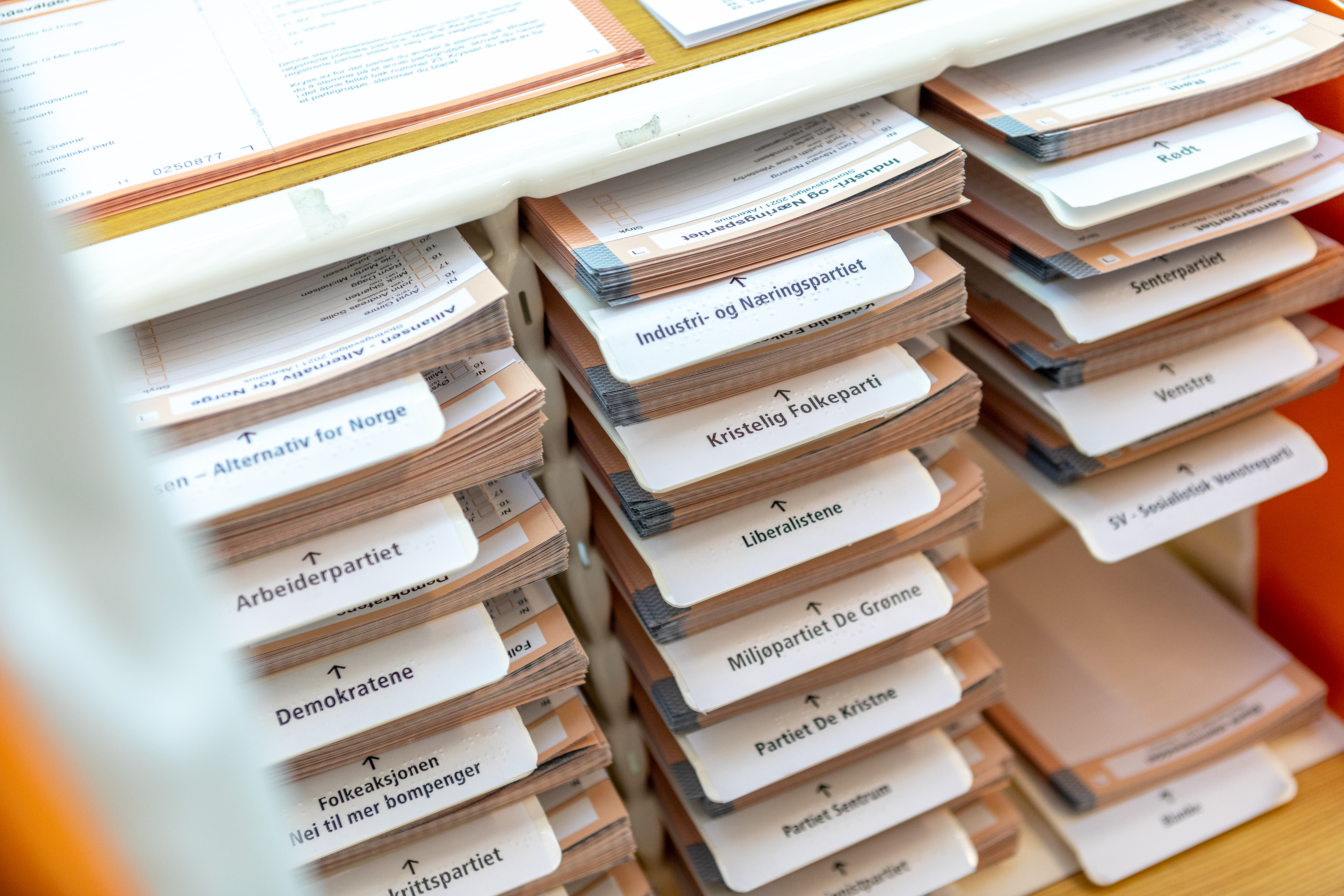 Stemmesedler ligger i hyller i et valgavlukke.