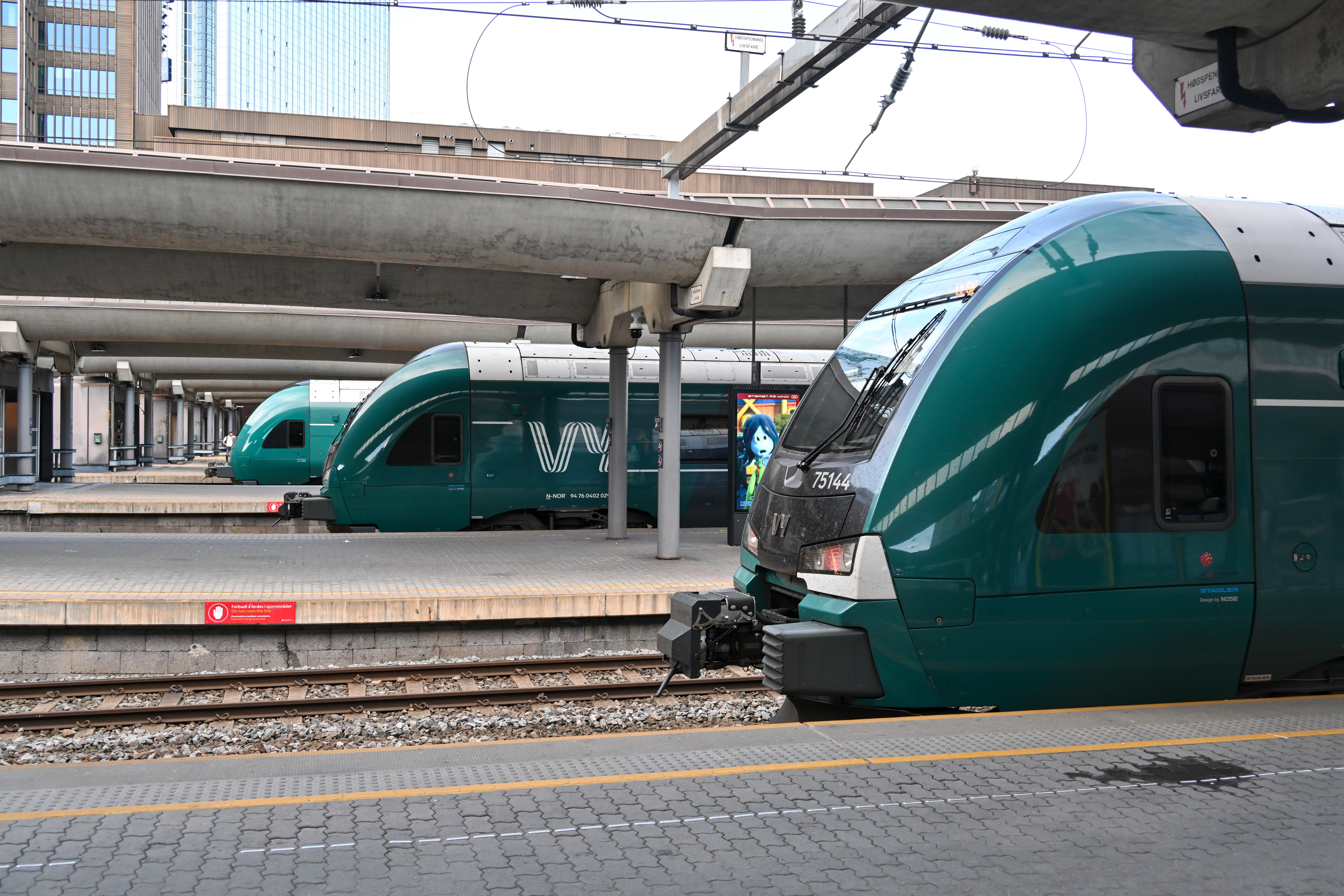 Tre grønne VY-tog står på en togstasjon.